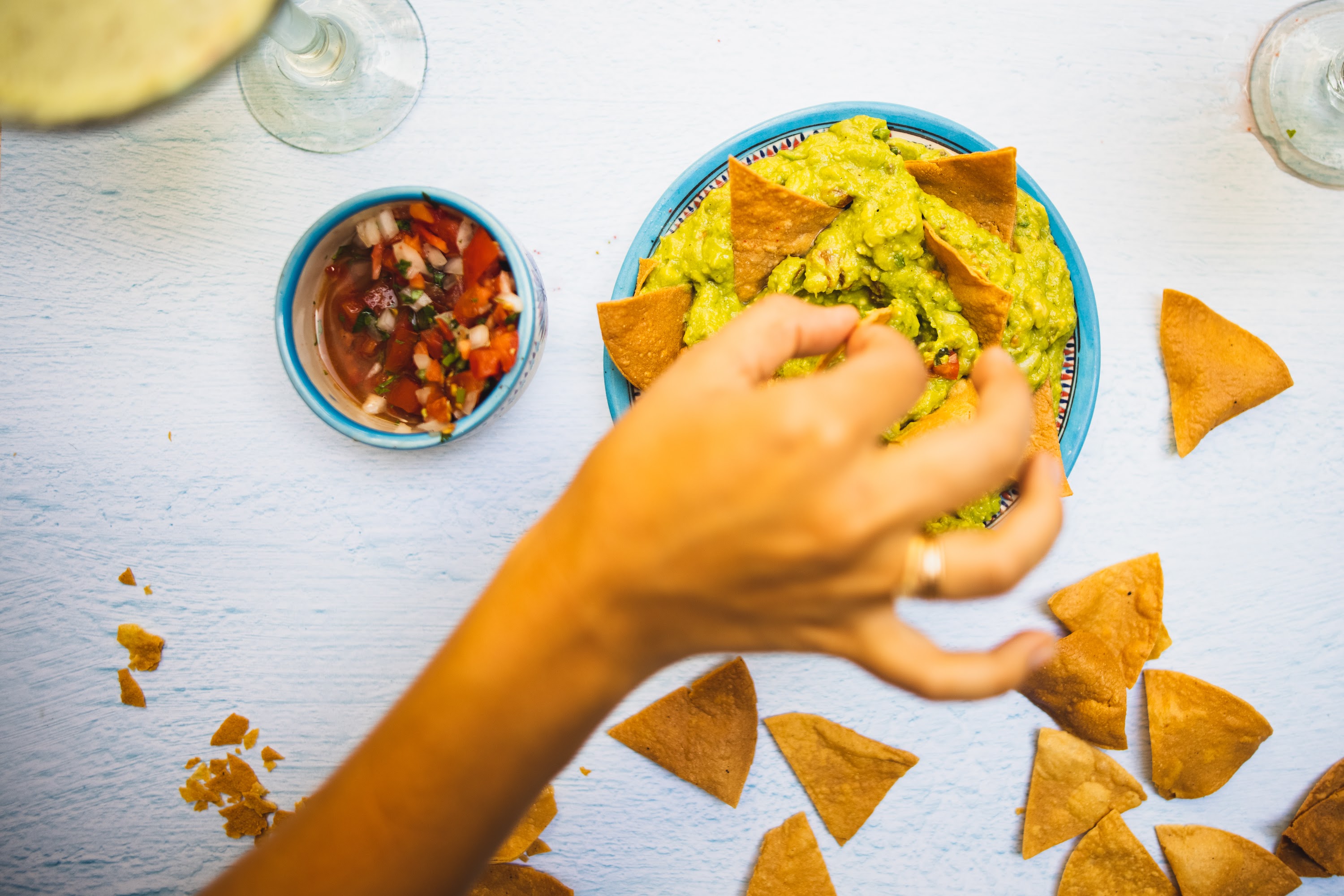 Hand Reaching for Guacamole and Chips