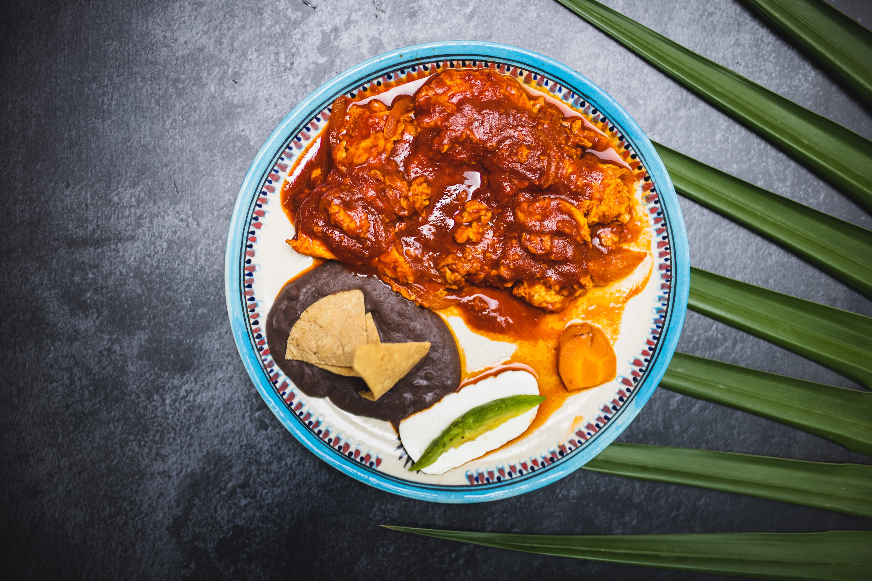 Mexican-style dish with red sauce, black beans, and avocado