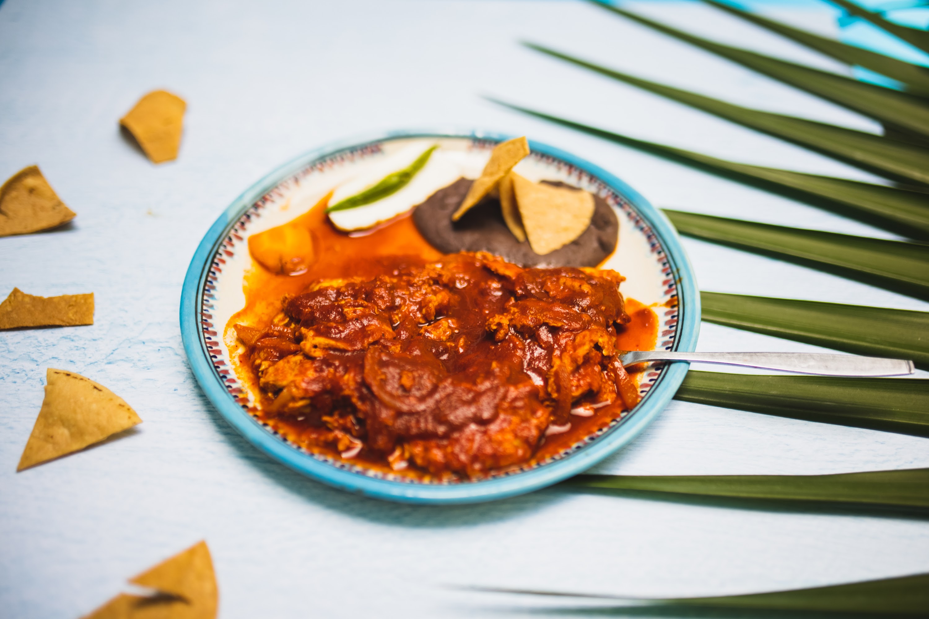 Mexican-style dish with red sauce, refried beans, lime, and tortilla chips