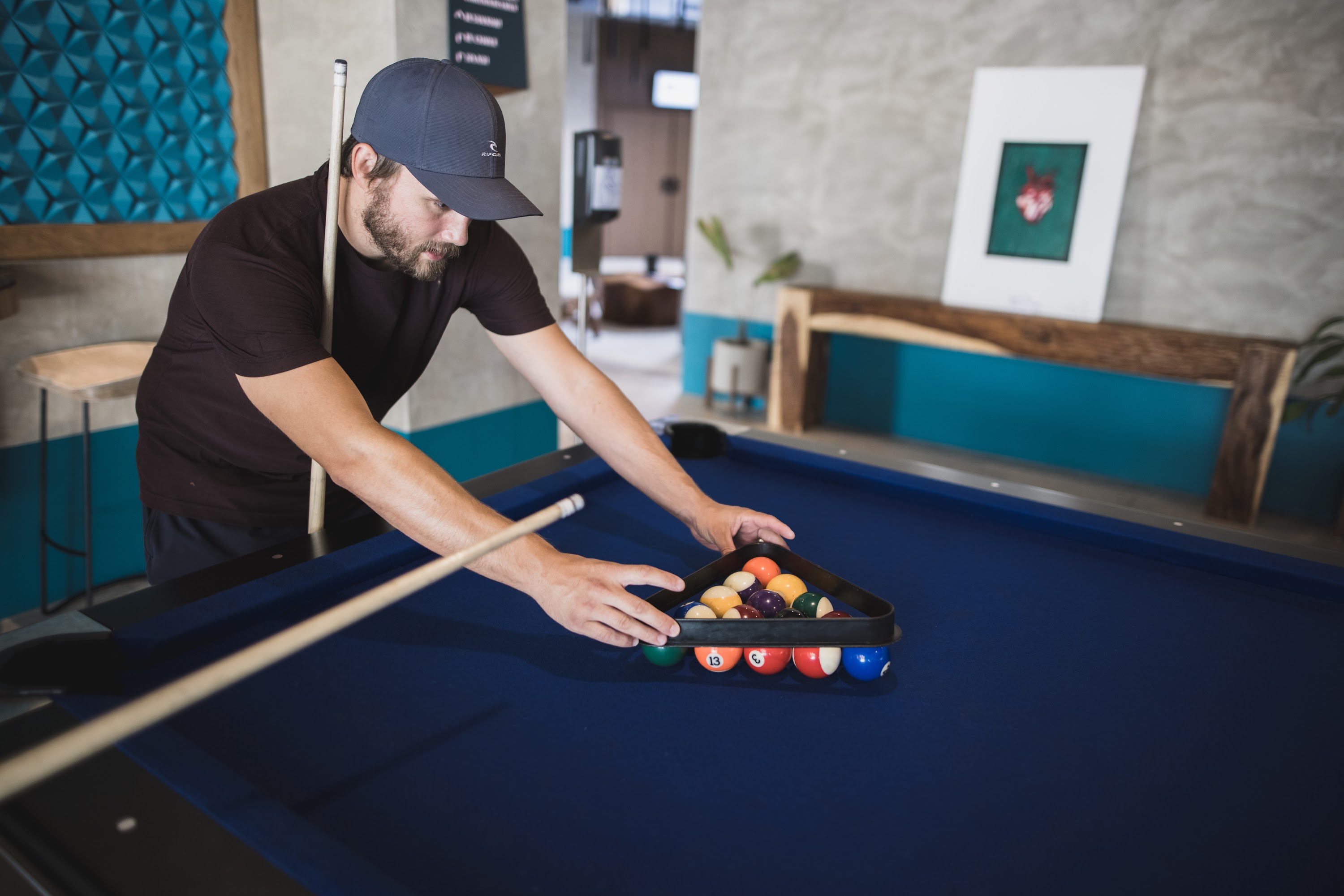 Man Setting Up Pool Balls on a Blue Table