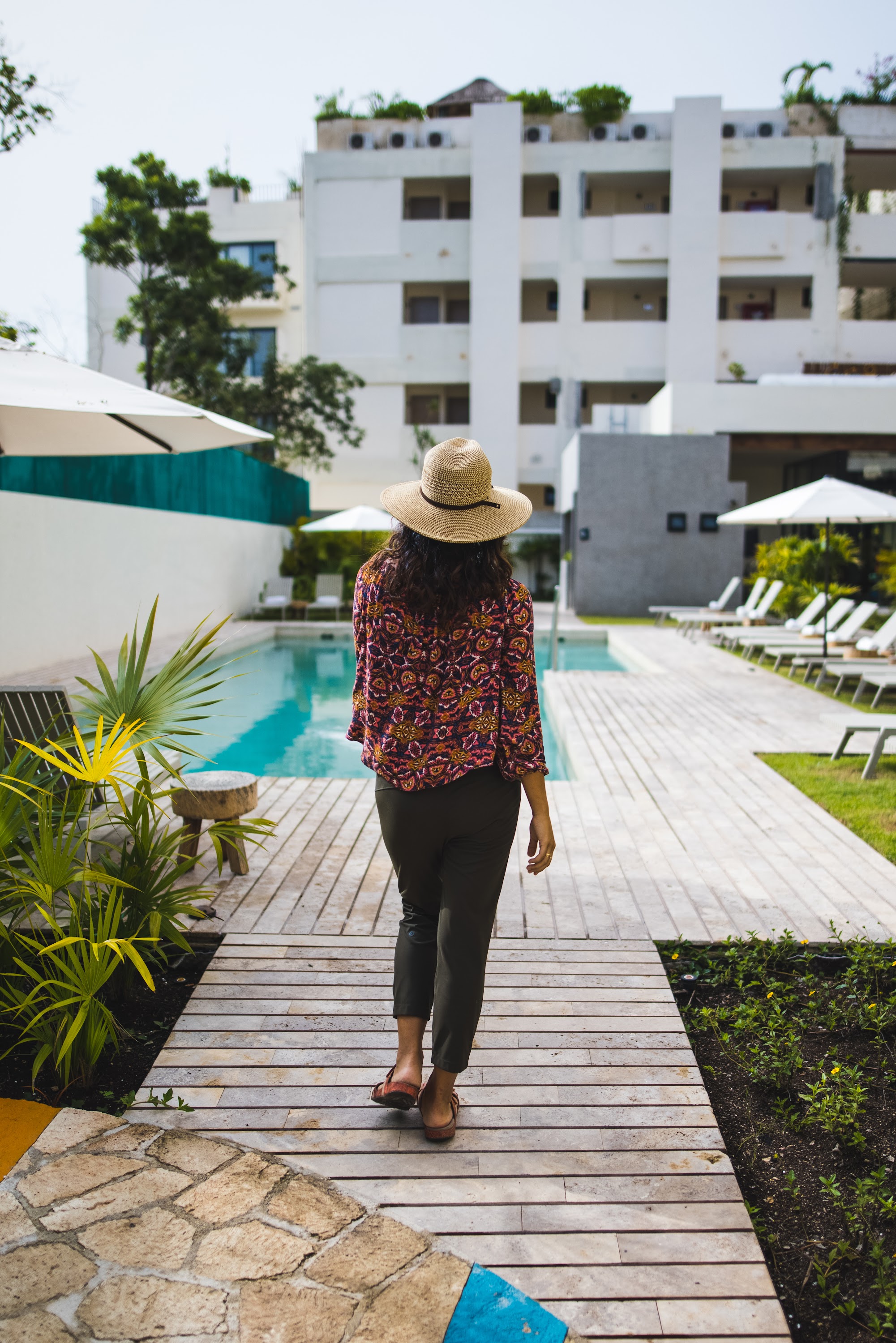 Woman Walking Toward Pool in Resort Setting