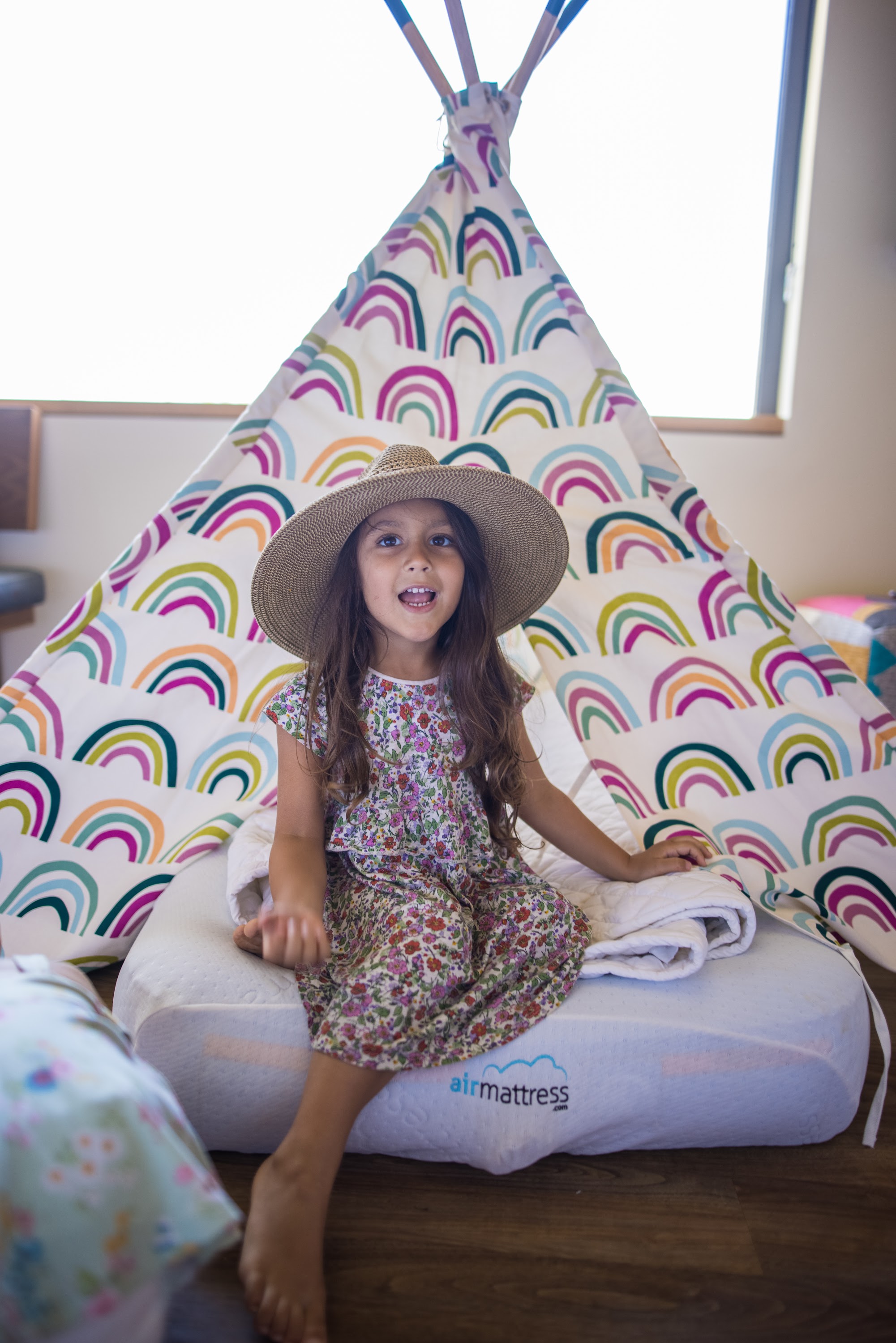 Young Girl in Straw Hat Sitting Inside Rainbow-Teepee