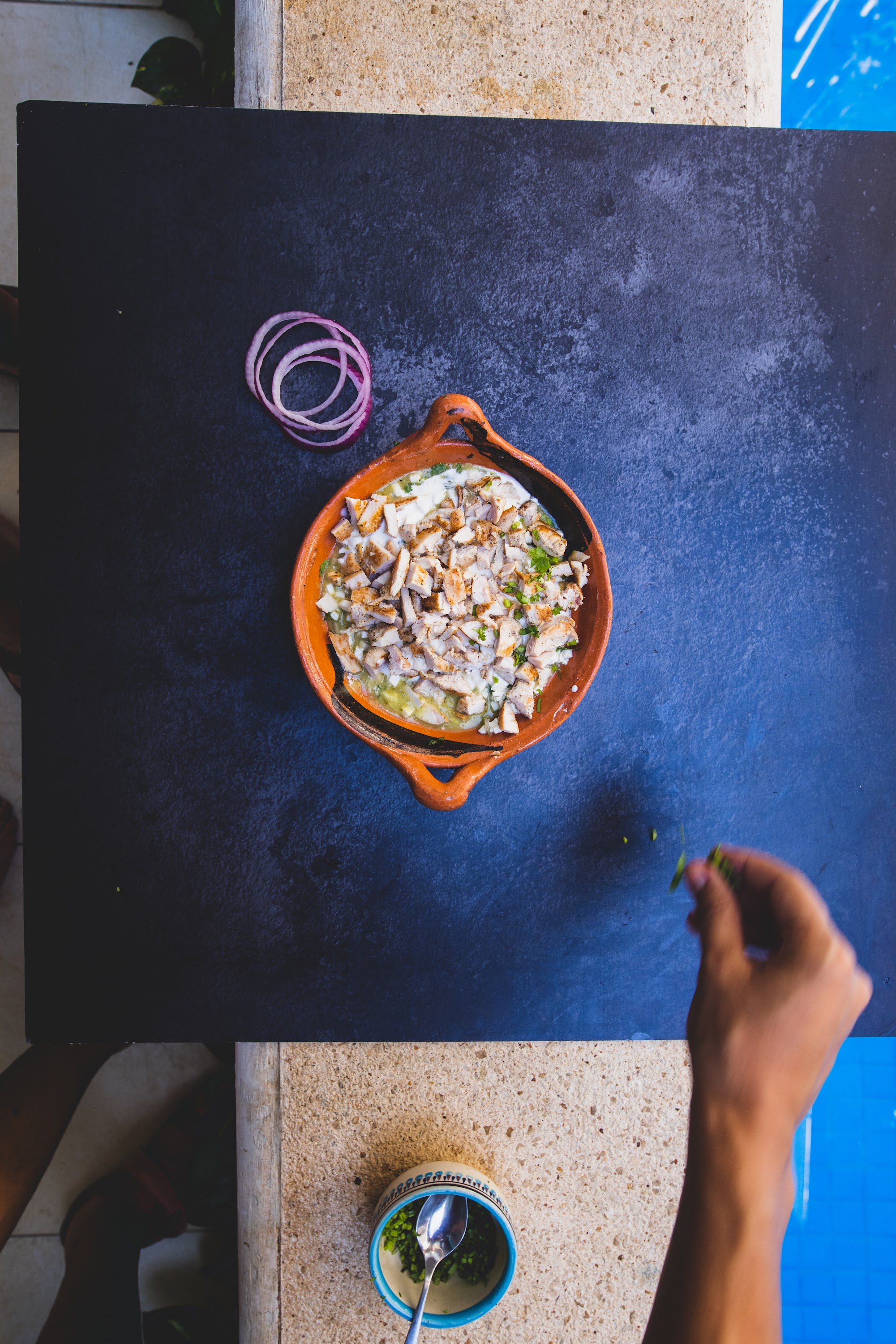 Top-down view of a traditional Mexican dish being garnished