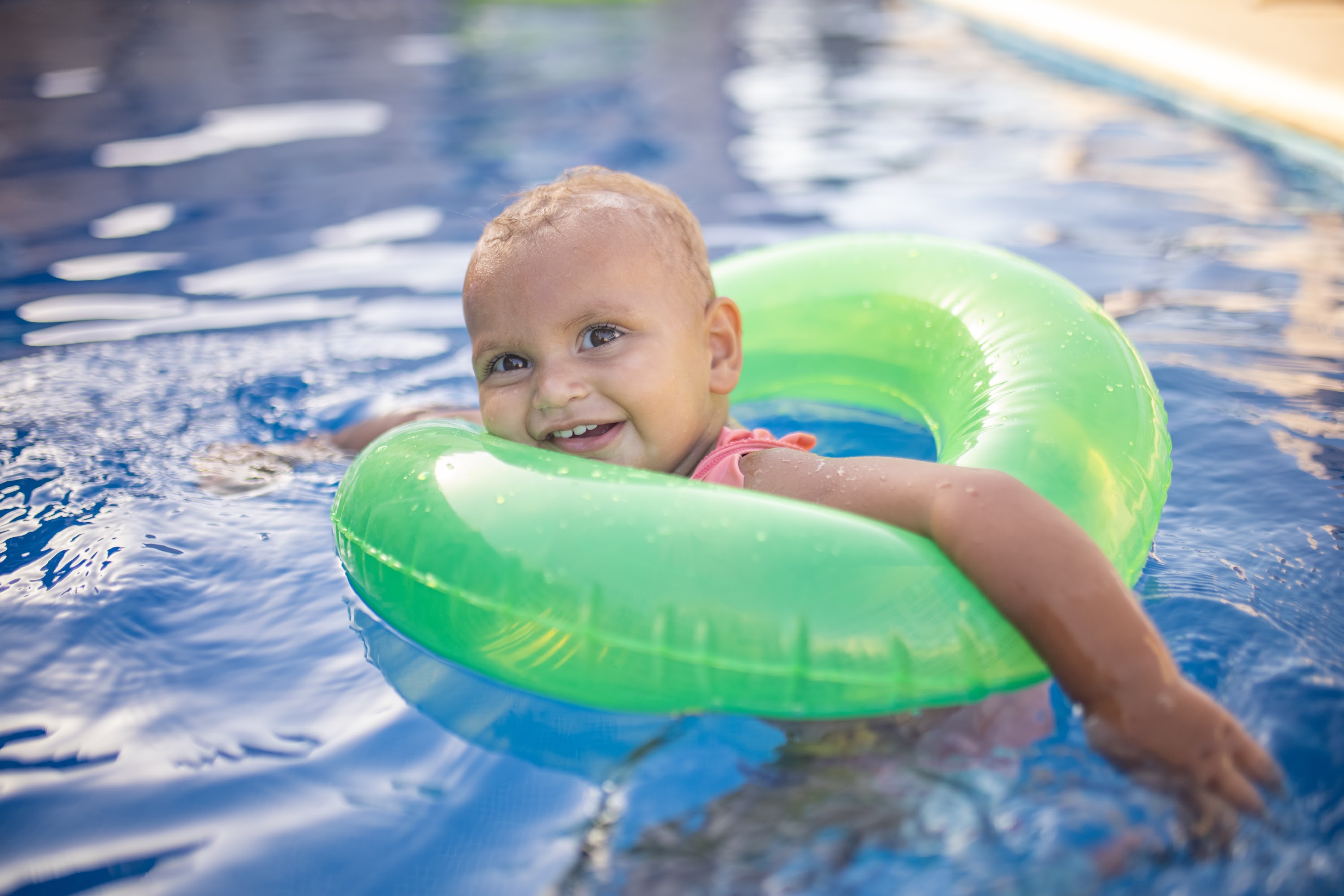 Happy Baby Swimming in Pool with Green Floatie