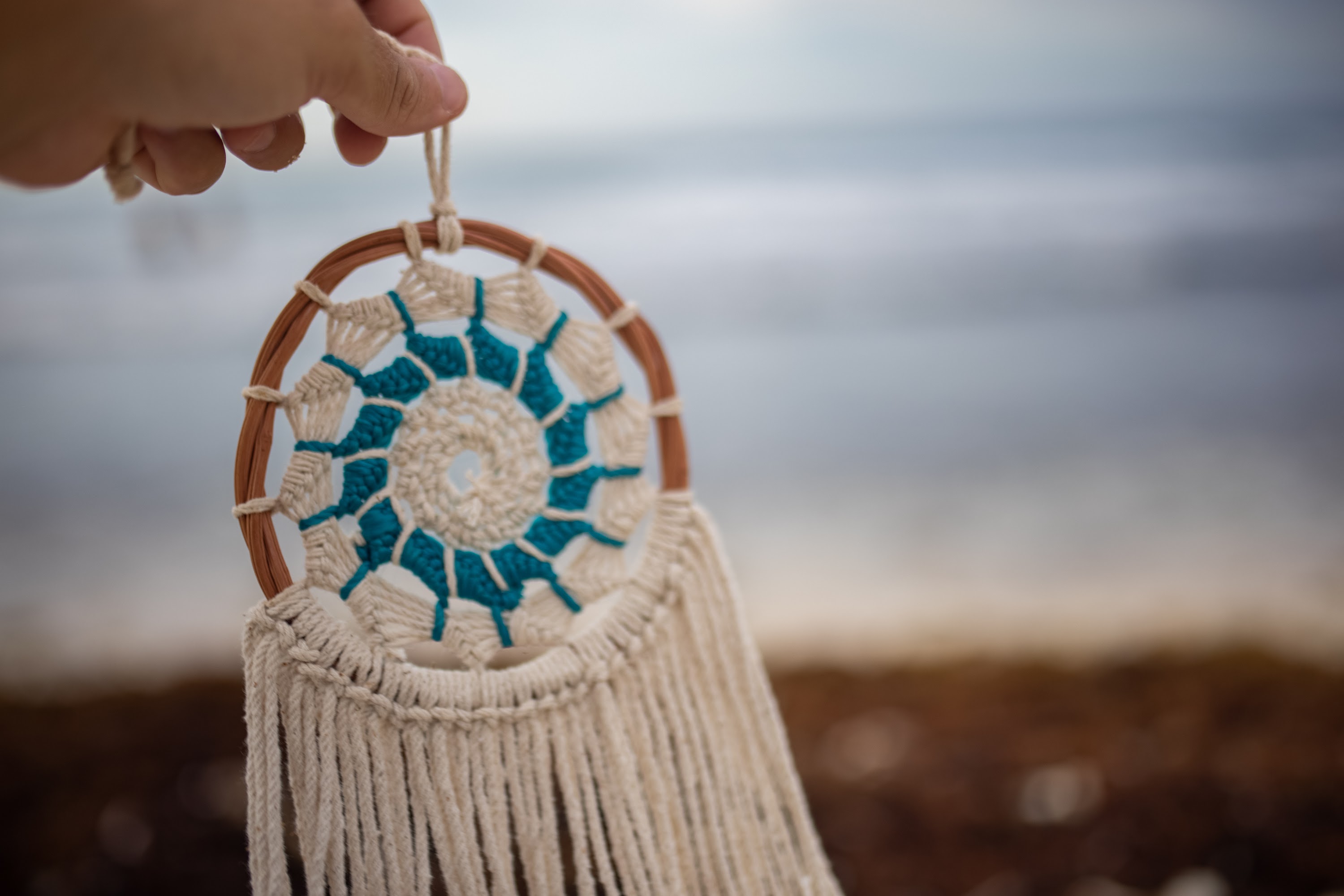 Hand Holding Macramé Dreamcatcher at the Beach