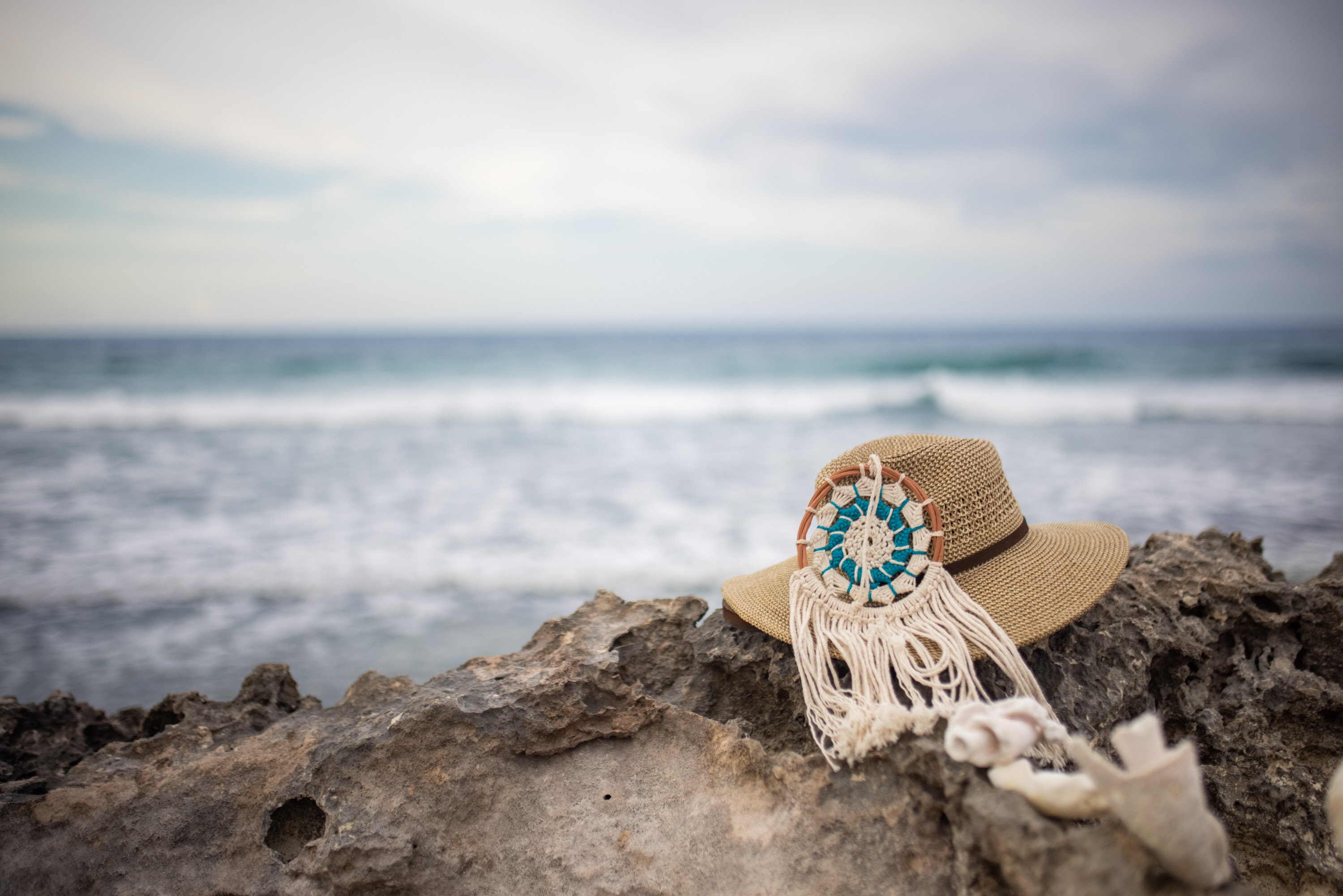 Straw Hat with Macrame Decoration on Rocky Beach