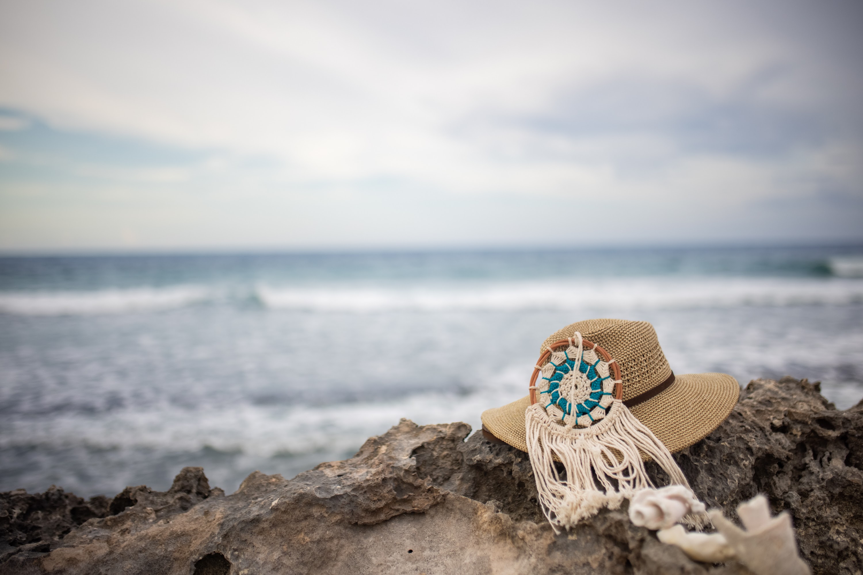 Straw Hat with Macrame Decoration on Rocky Beach