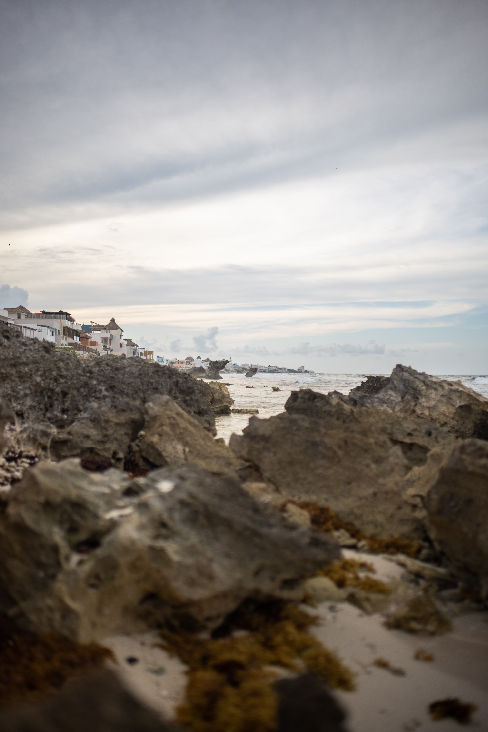 Rocks and Coastal Village Under Overcast Sky