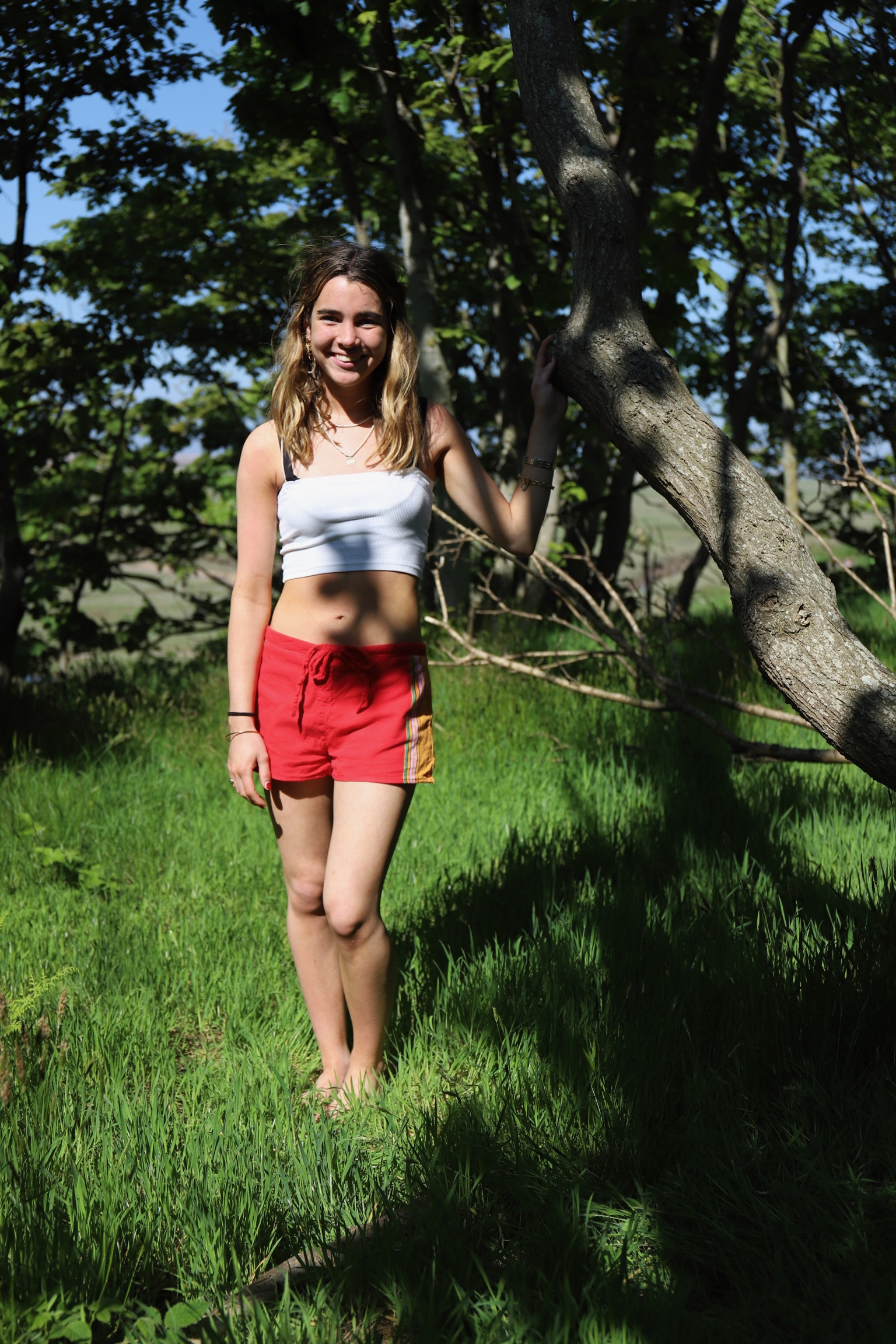 Young Woman Leaning Against Tree in Wooded Setting