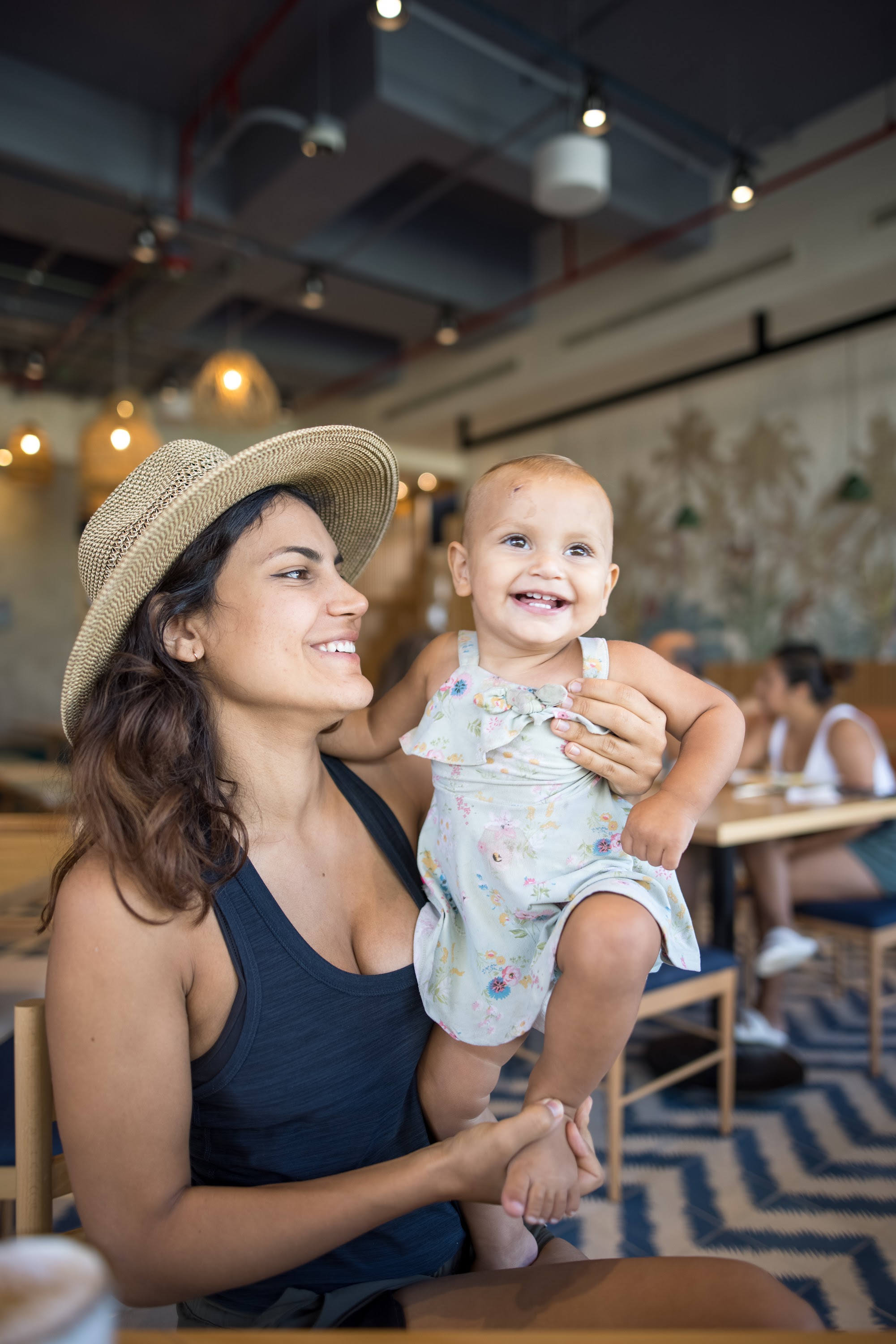 Smiling Mother Holding Baby in Cafe