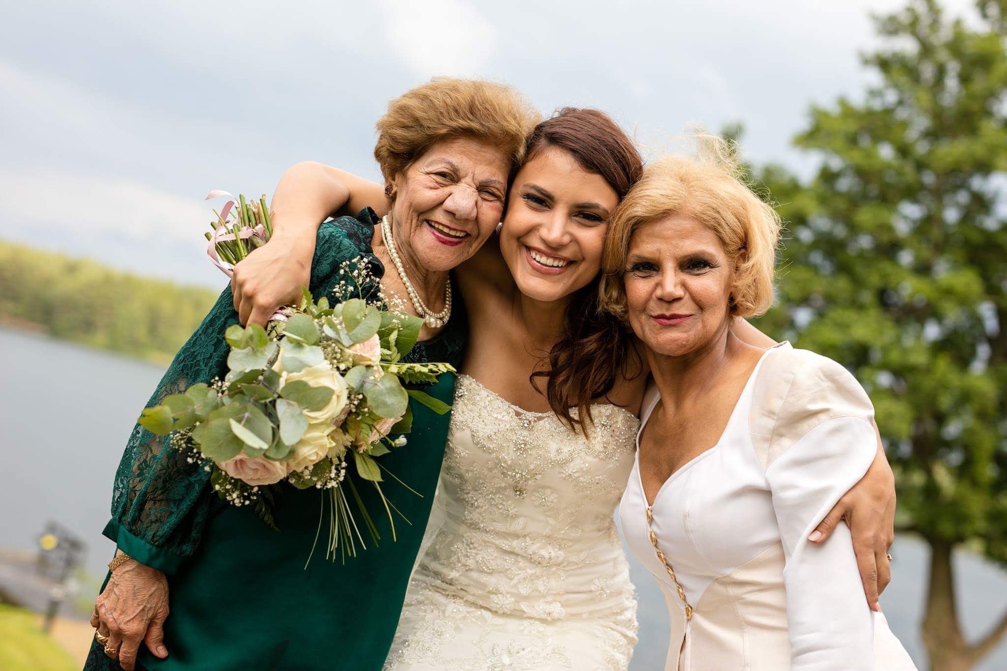 Bride with two older women outdoors by water