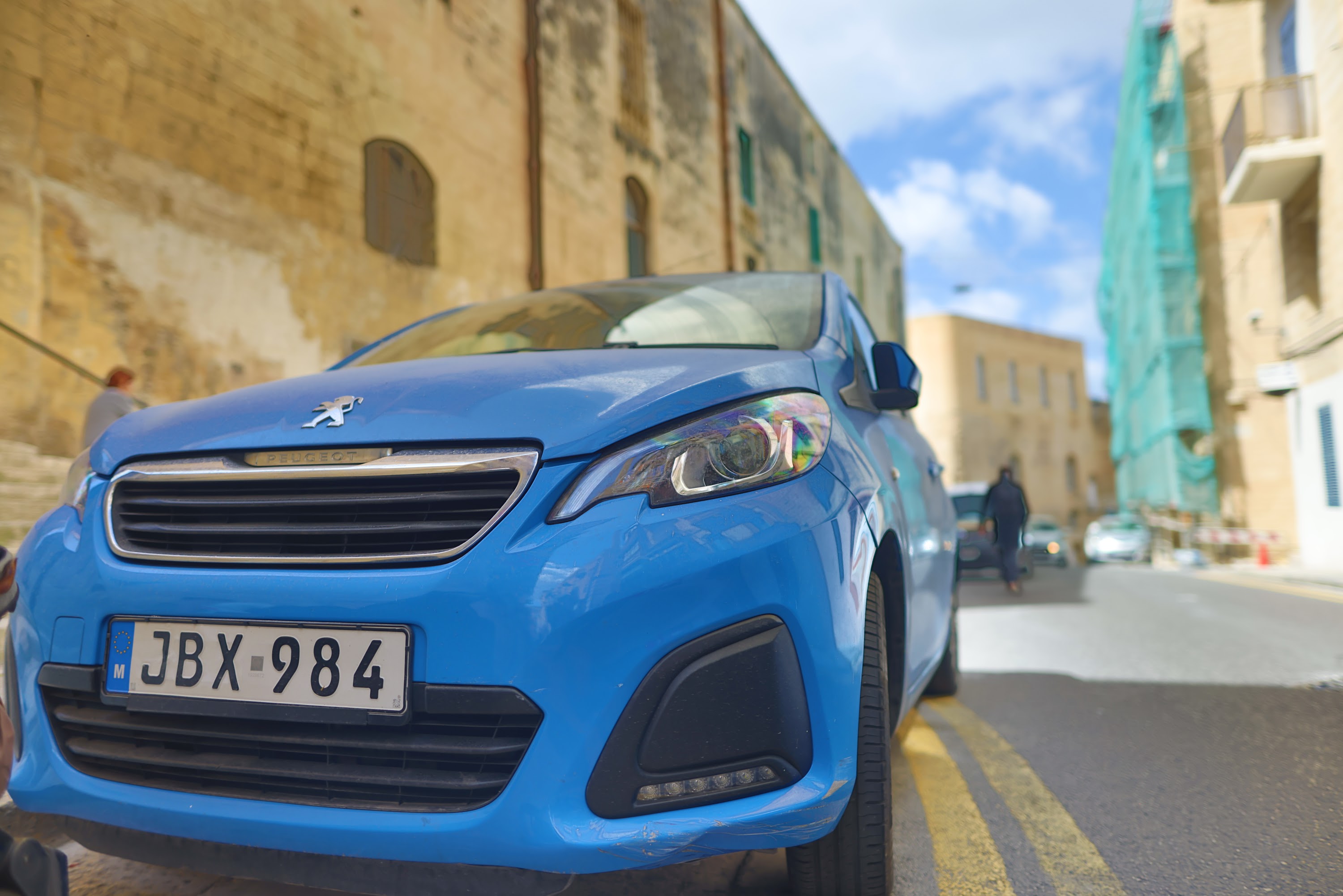 Blue Peugeot Car Parked on Street in Historic Town