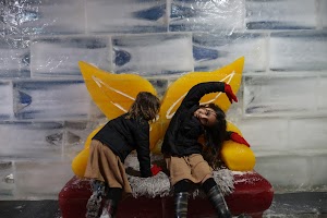 Two Girls Playing on Ice Sculpture with Yellow Wings