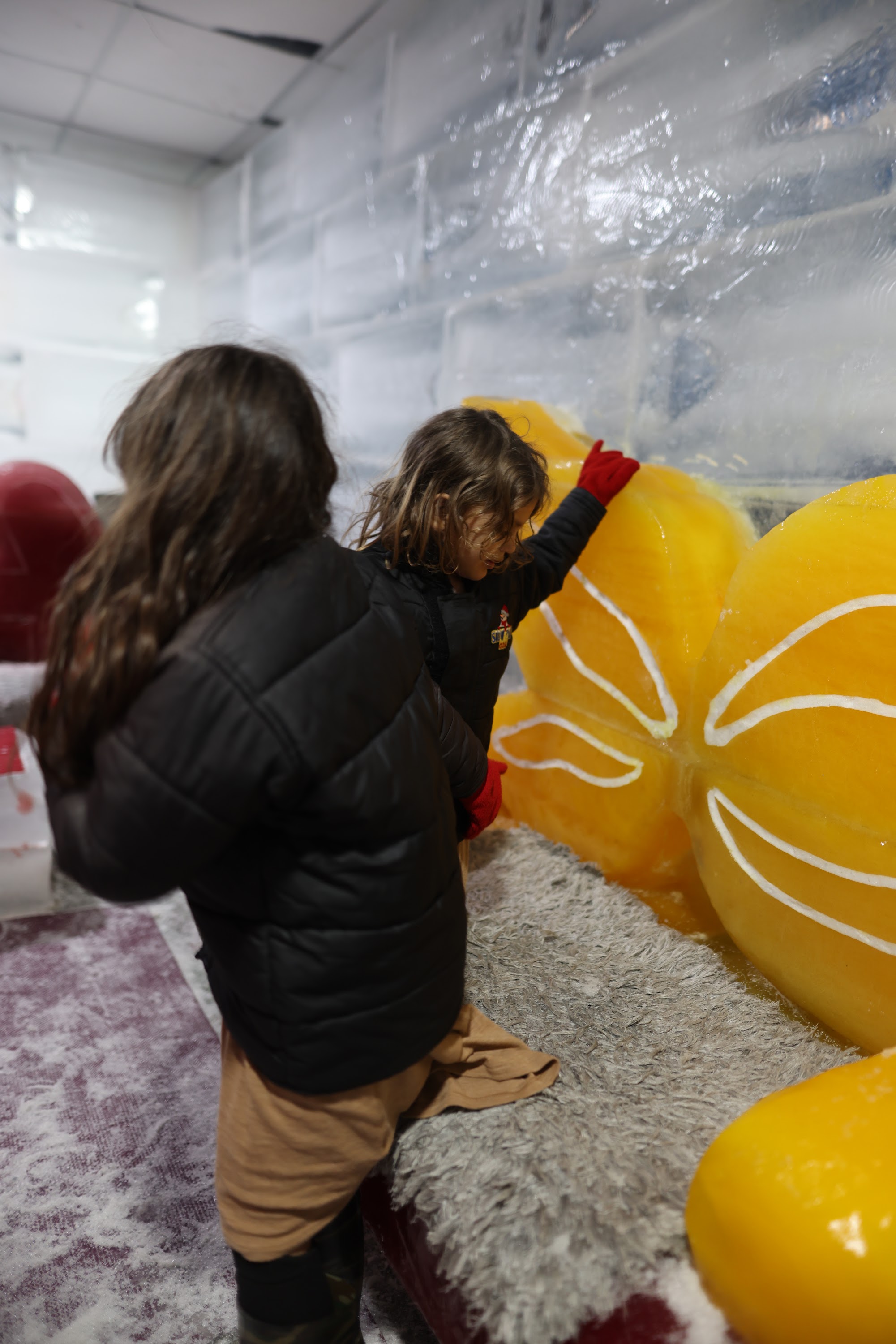 Children Interacting with Large Yellow Ice Sculptures