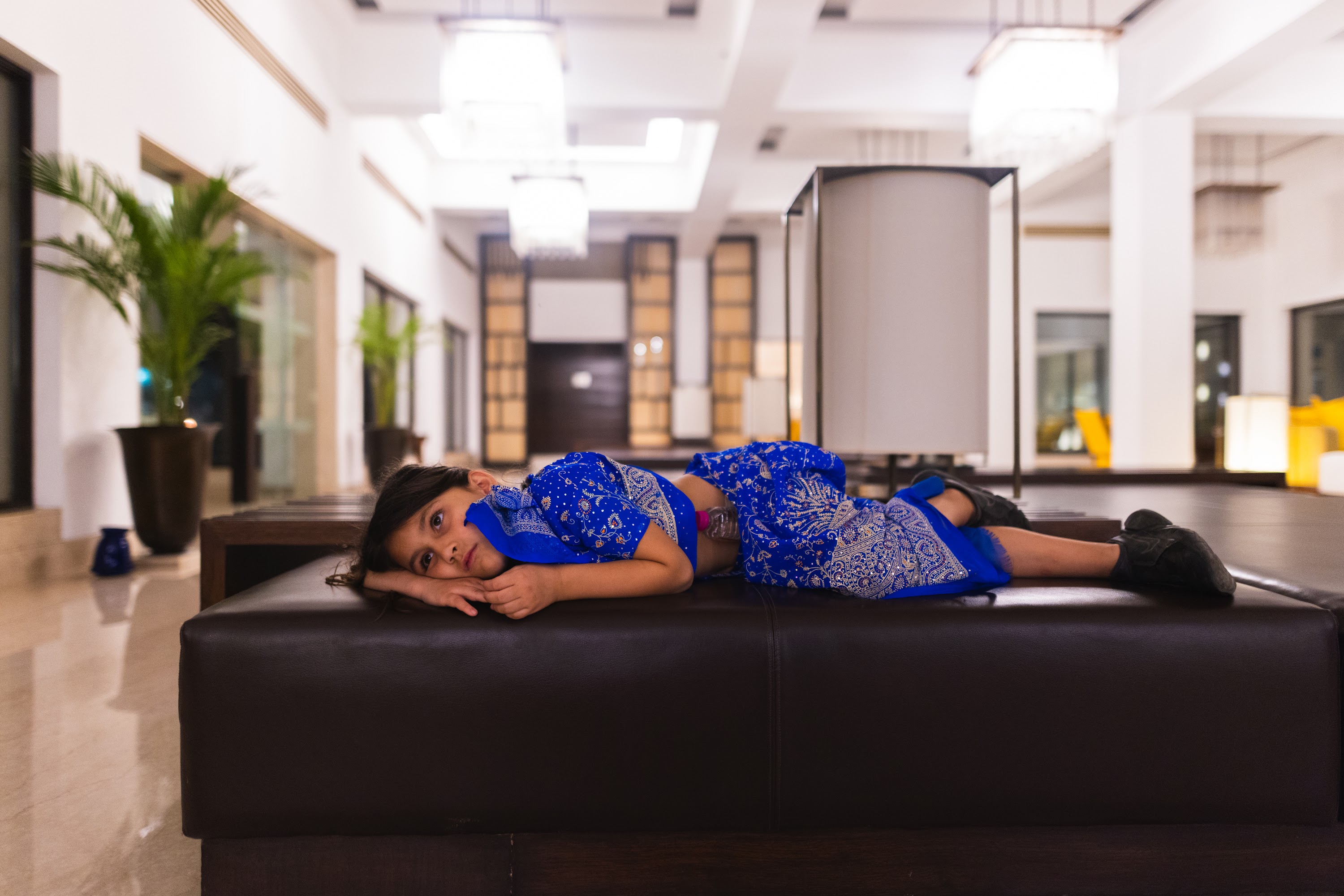 Young Girl Resting on Lobby Ottoman in Blue Traditional Attire