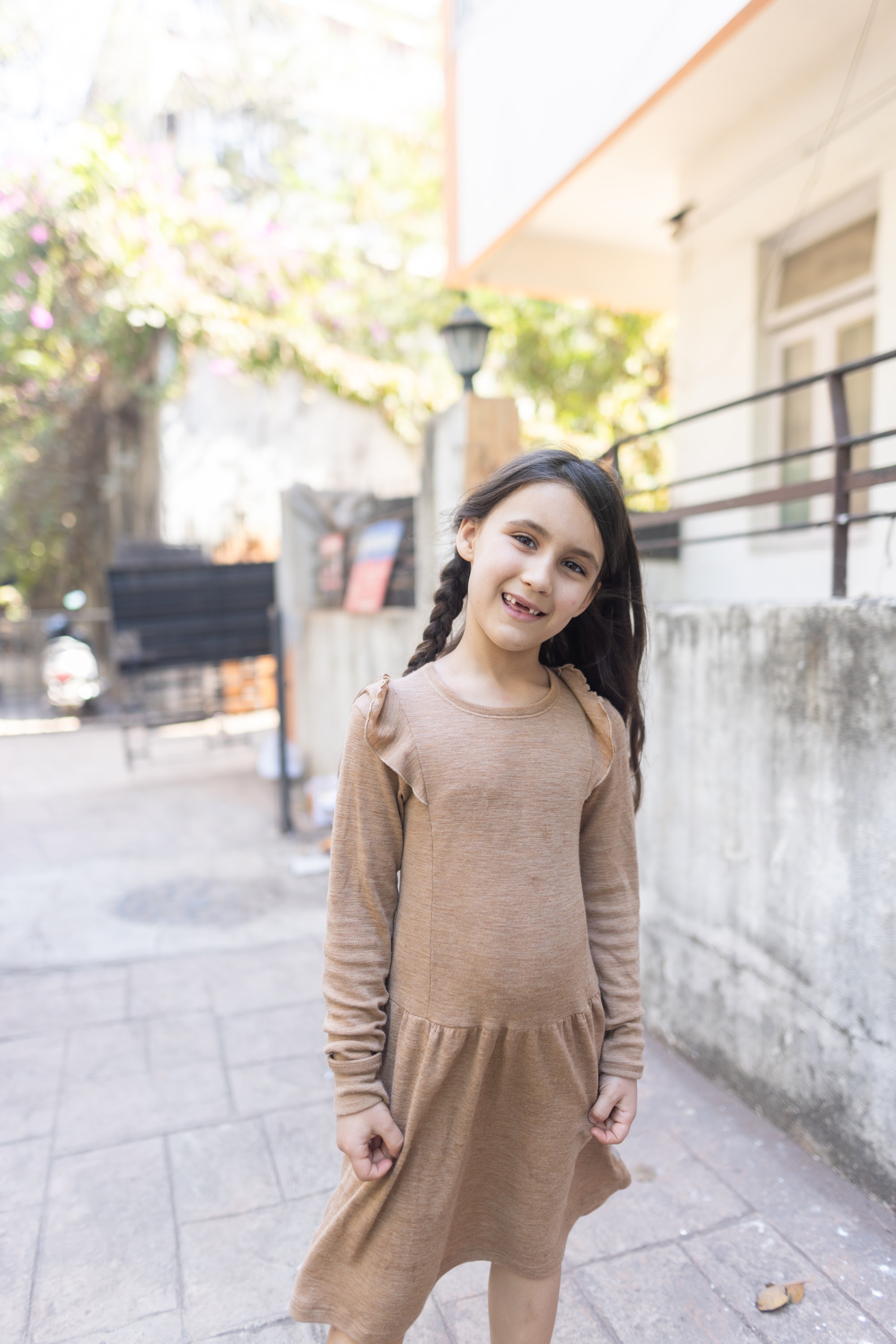 Girl Smiling in Beige Dress on Sidewalk