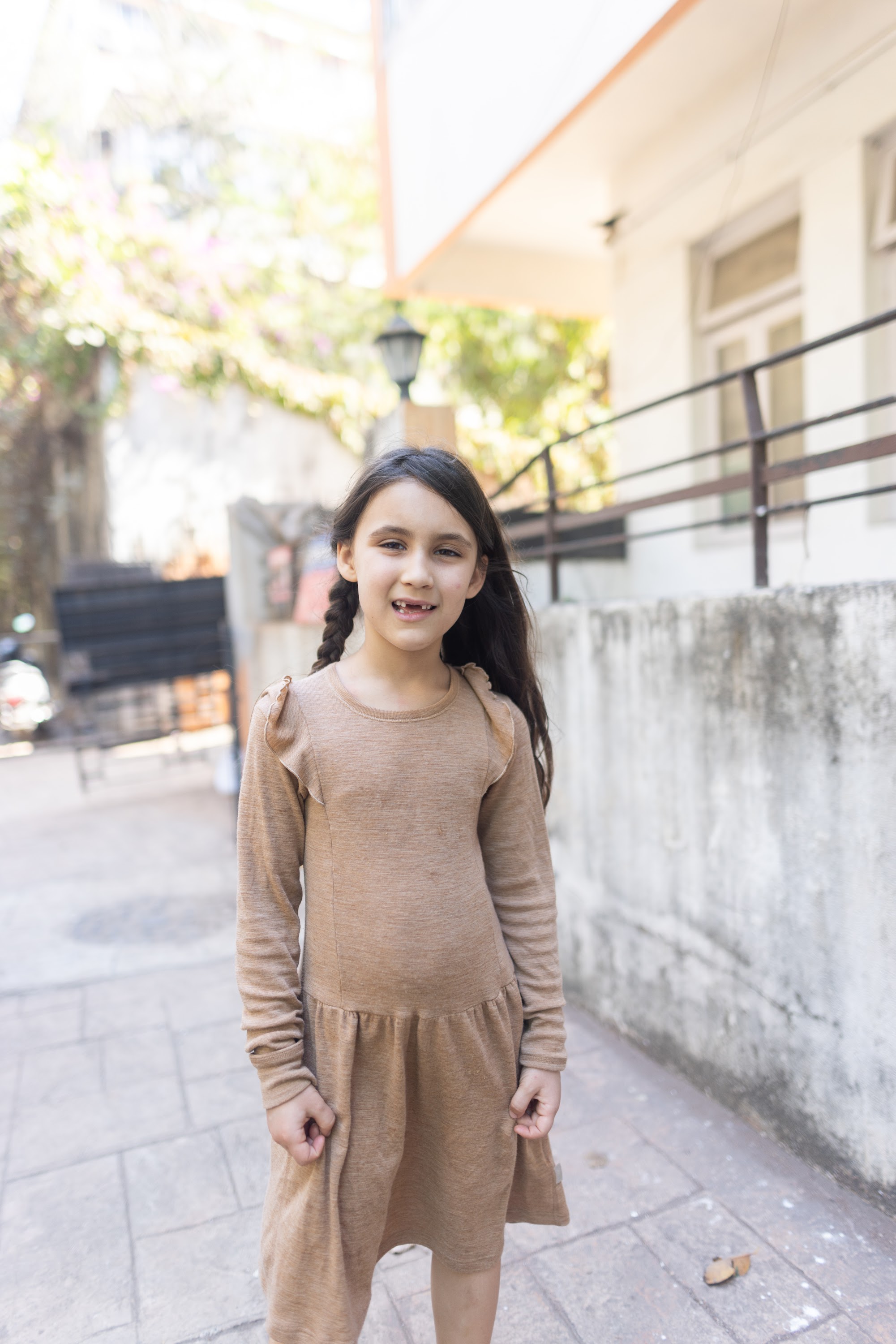 Young Girl in Brown Dress Standing Outdoors