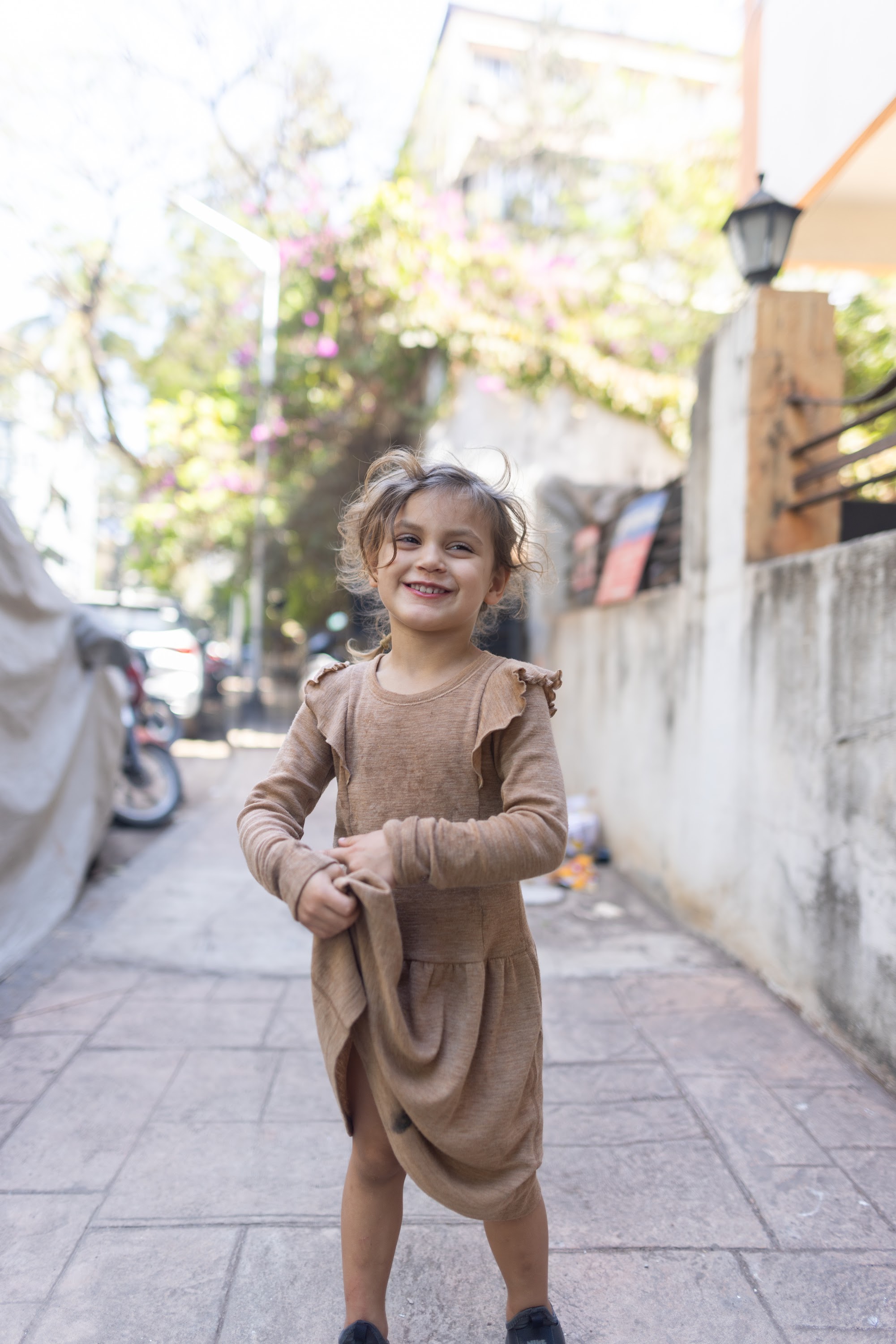 Smiling Girl in Brown Dress on a Sunlit Street