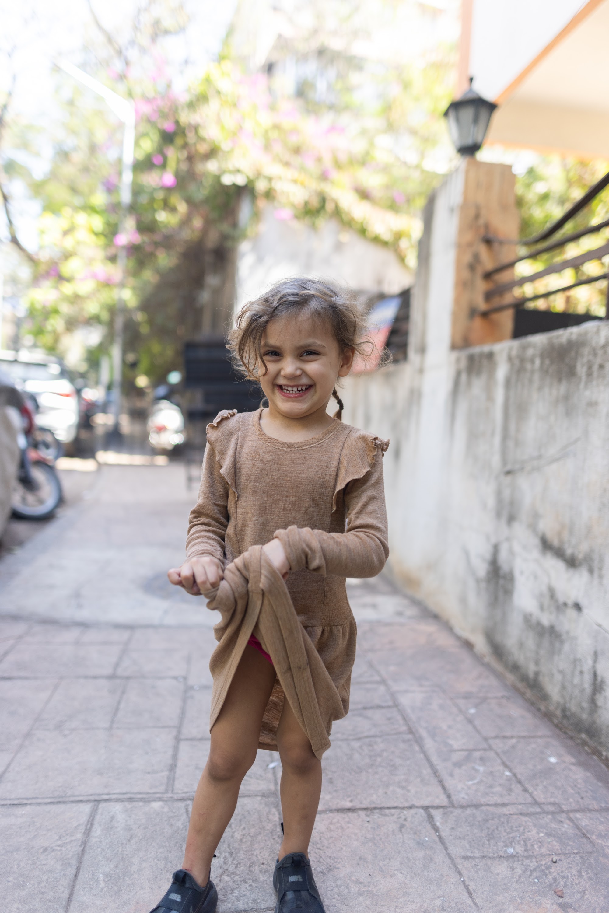 Smiling Girl Playing with Her Dress on a Sunny Street