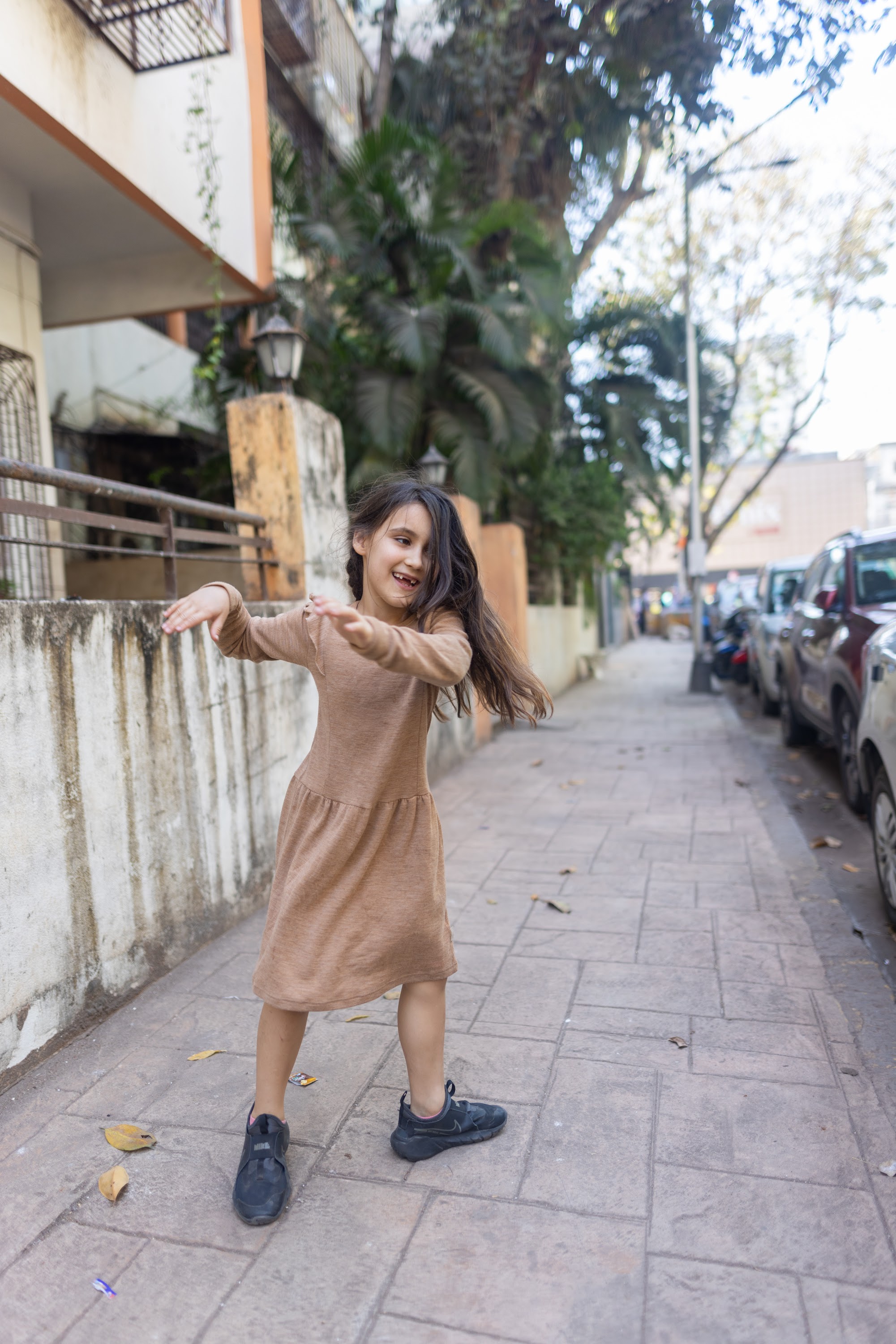 Joyful Girl Spinning on City Sidewalk