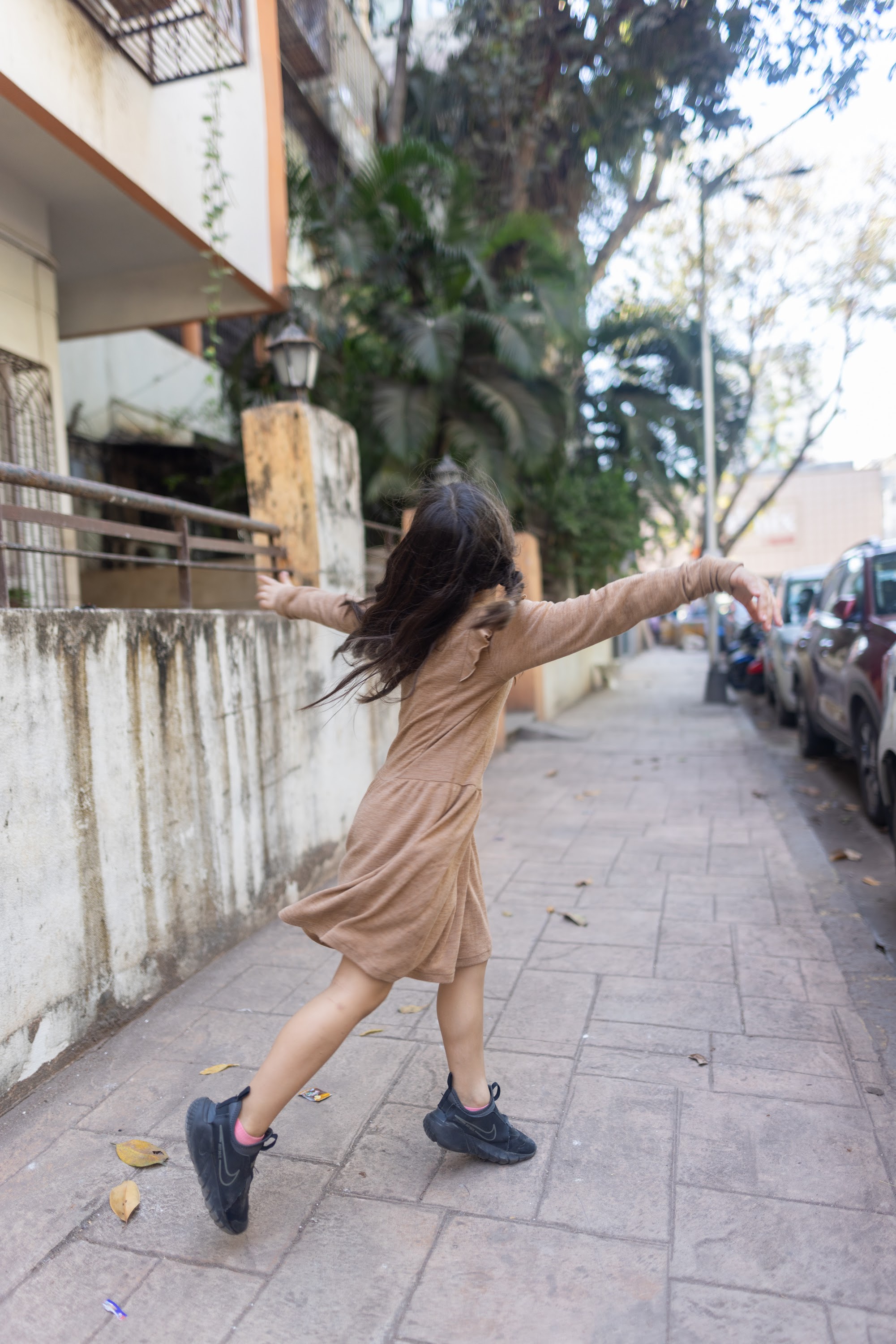 Girl Running with Arms Outstretched on Sidewalk