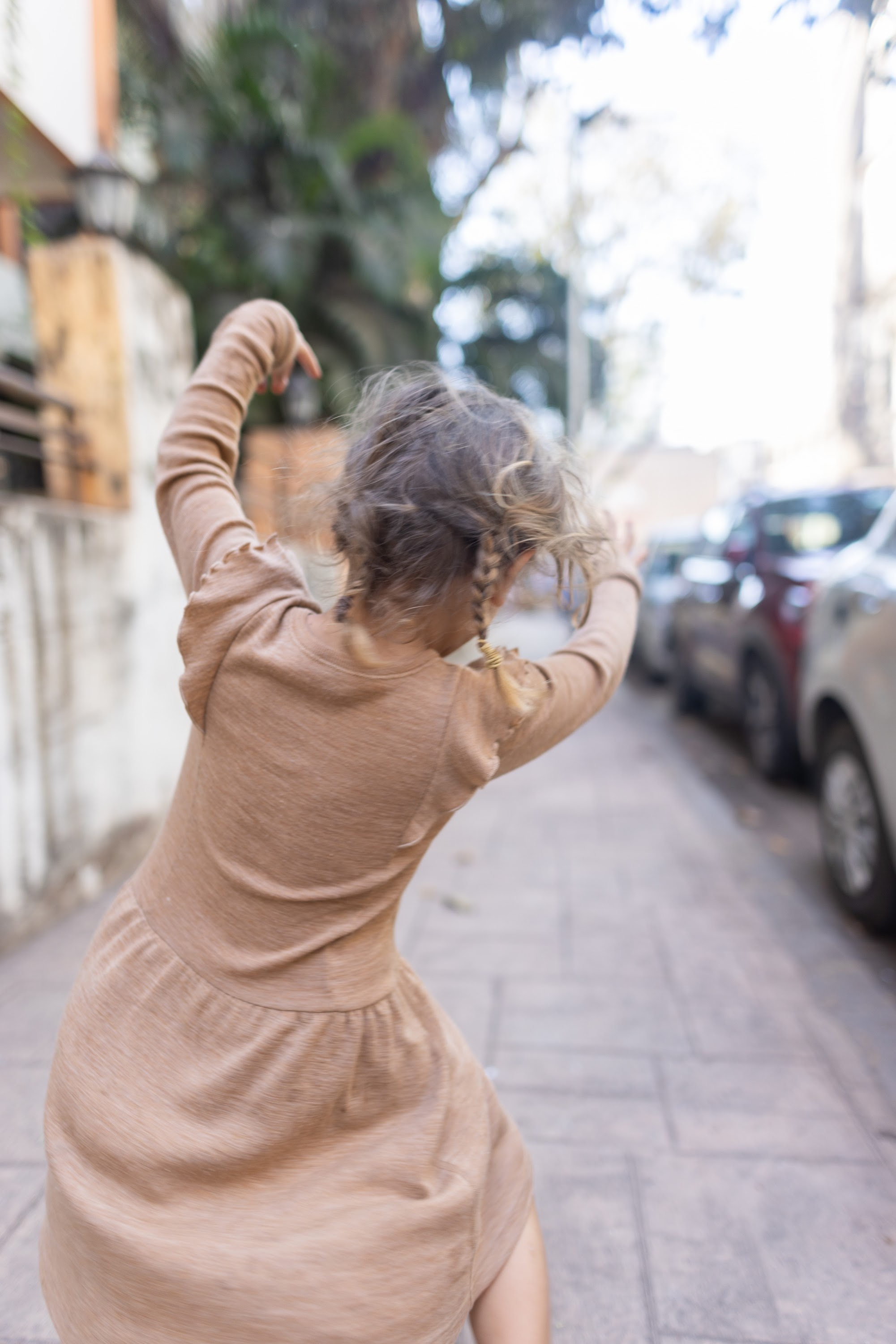 Joyful Girl Spinning on City Sidewalk