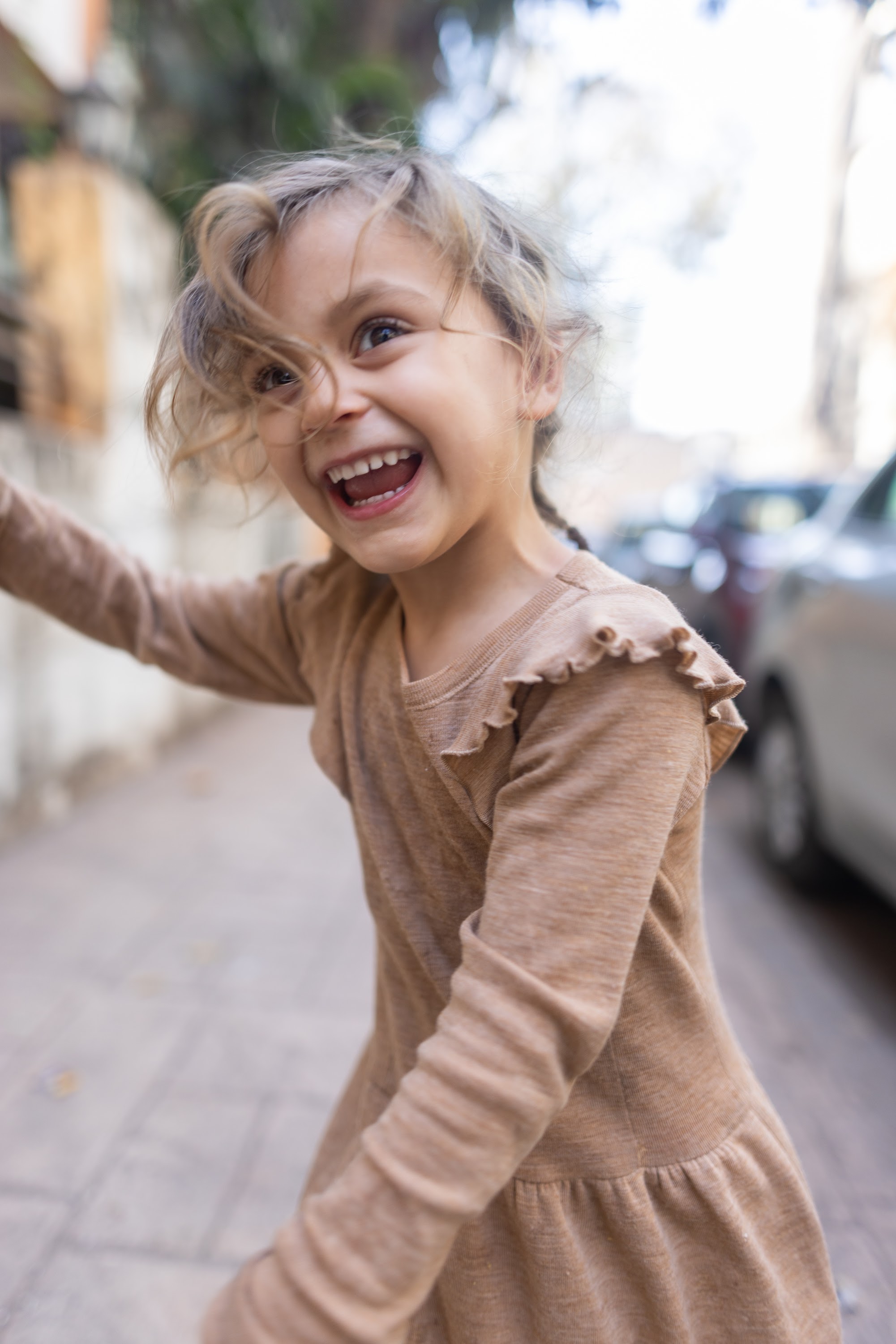 Joyful Girl Spinning on City Sidewalk