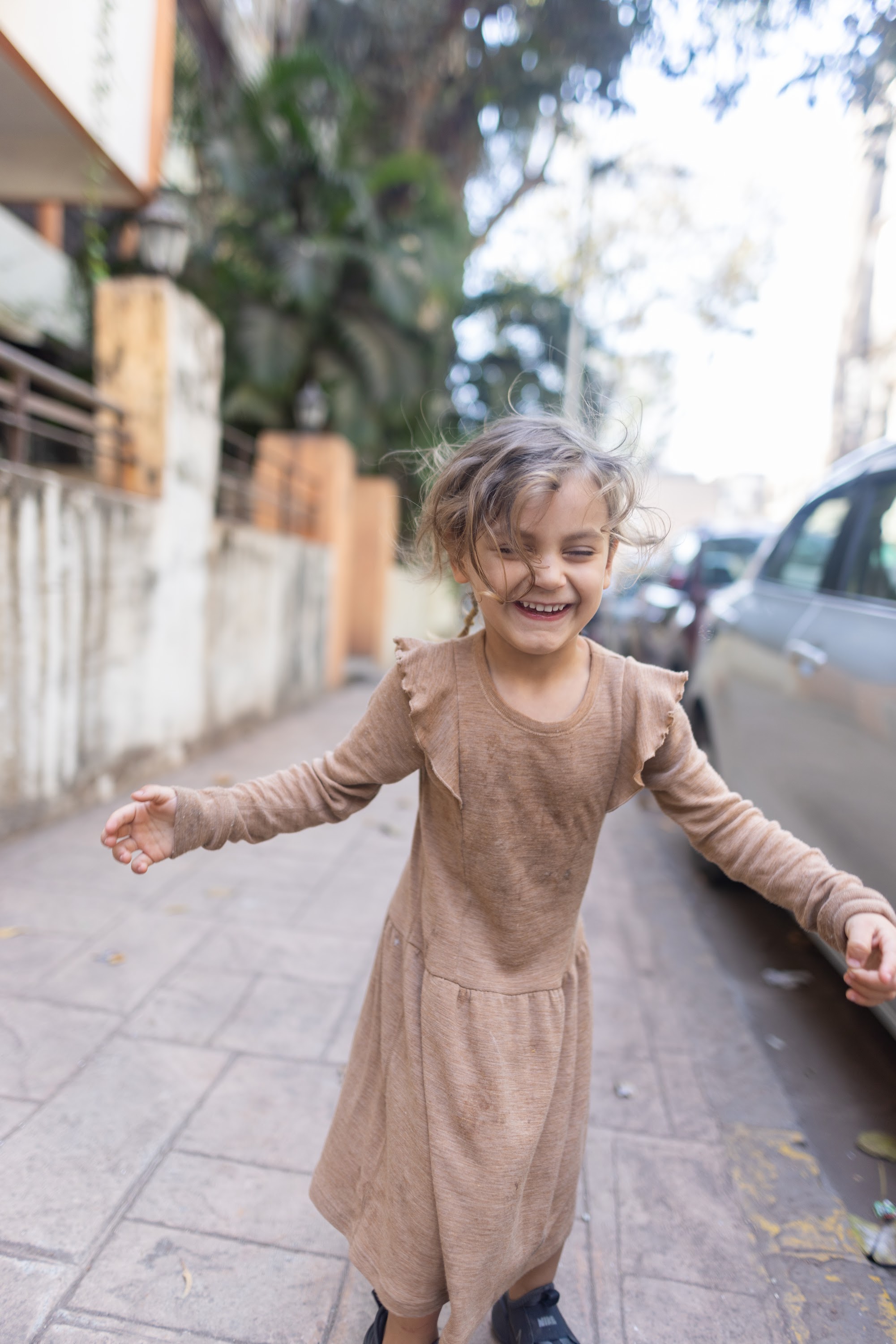 Joyful Girl Spinning on City Sidewalk
