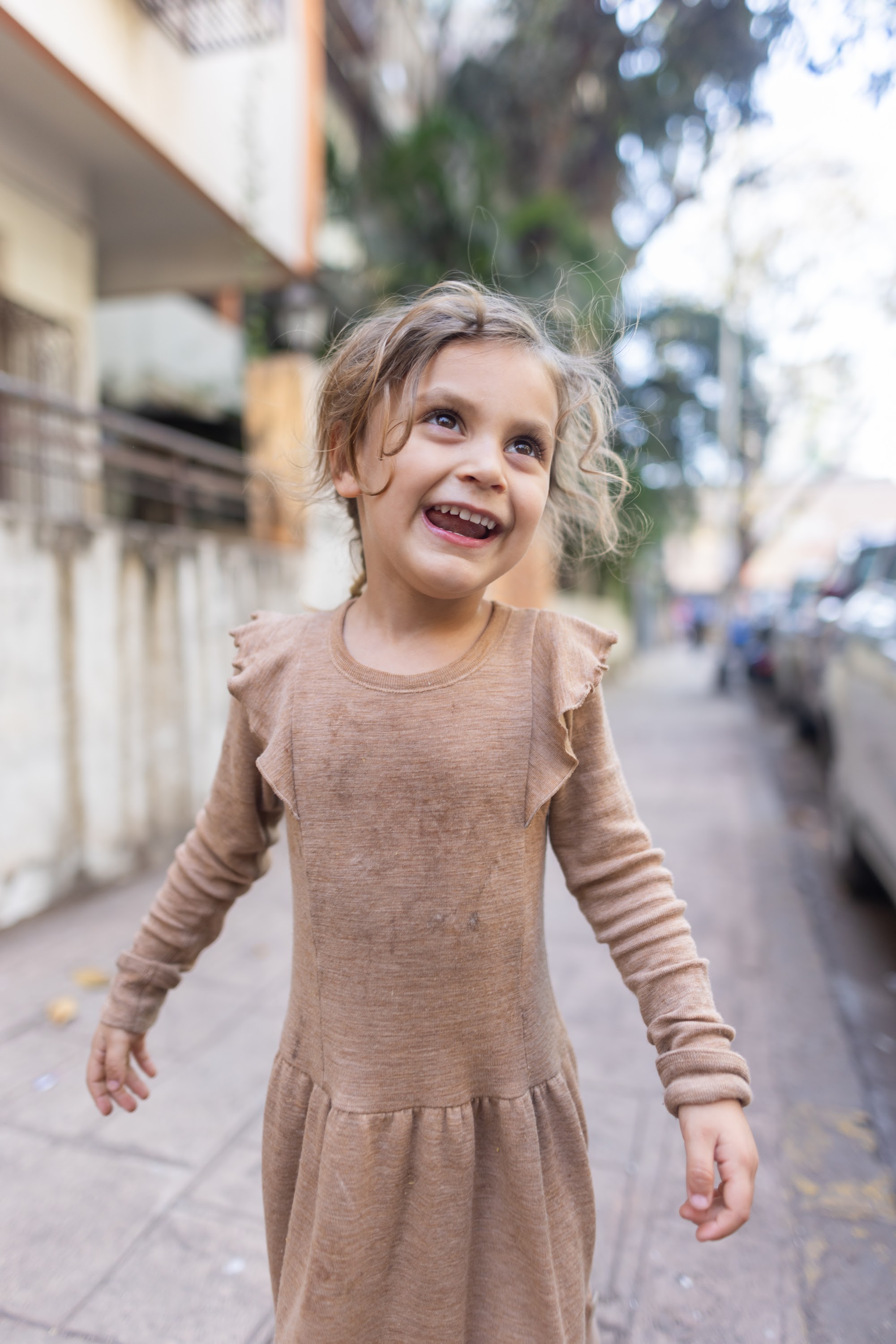 Joyful Girl Spinning on City Sidewalk