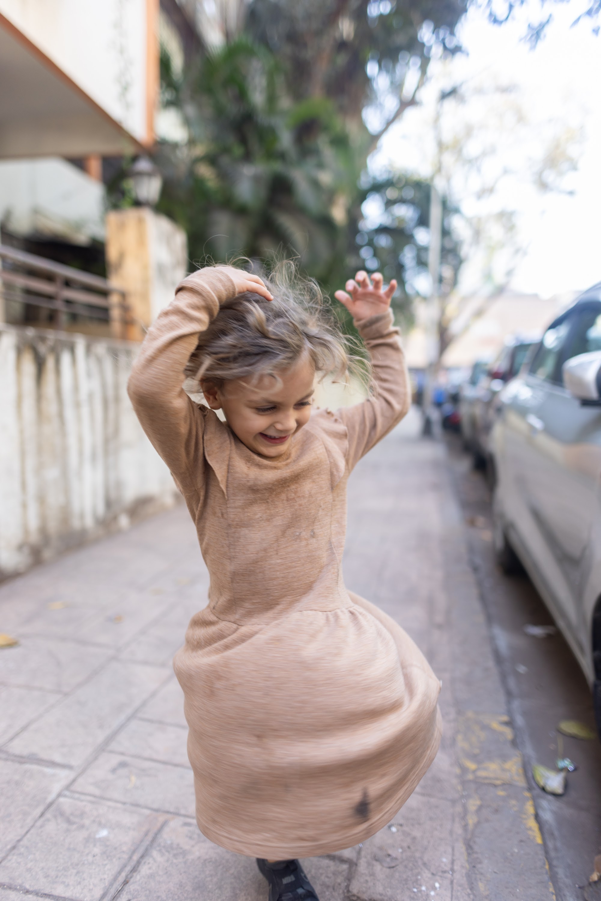 Joyful Girl Spinning on City Sidewalk