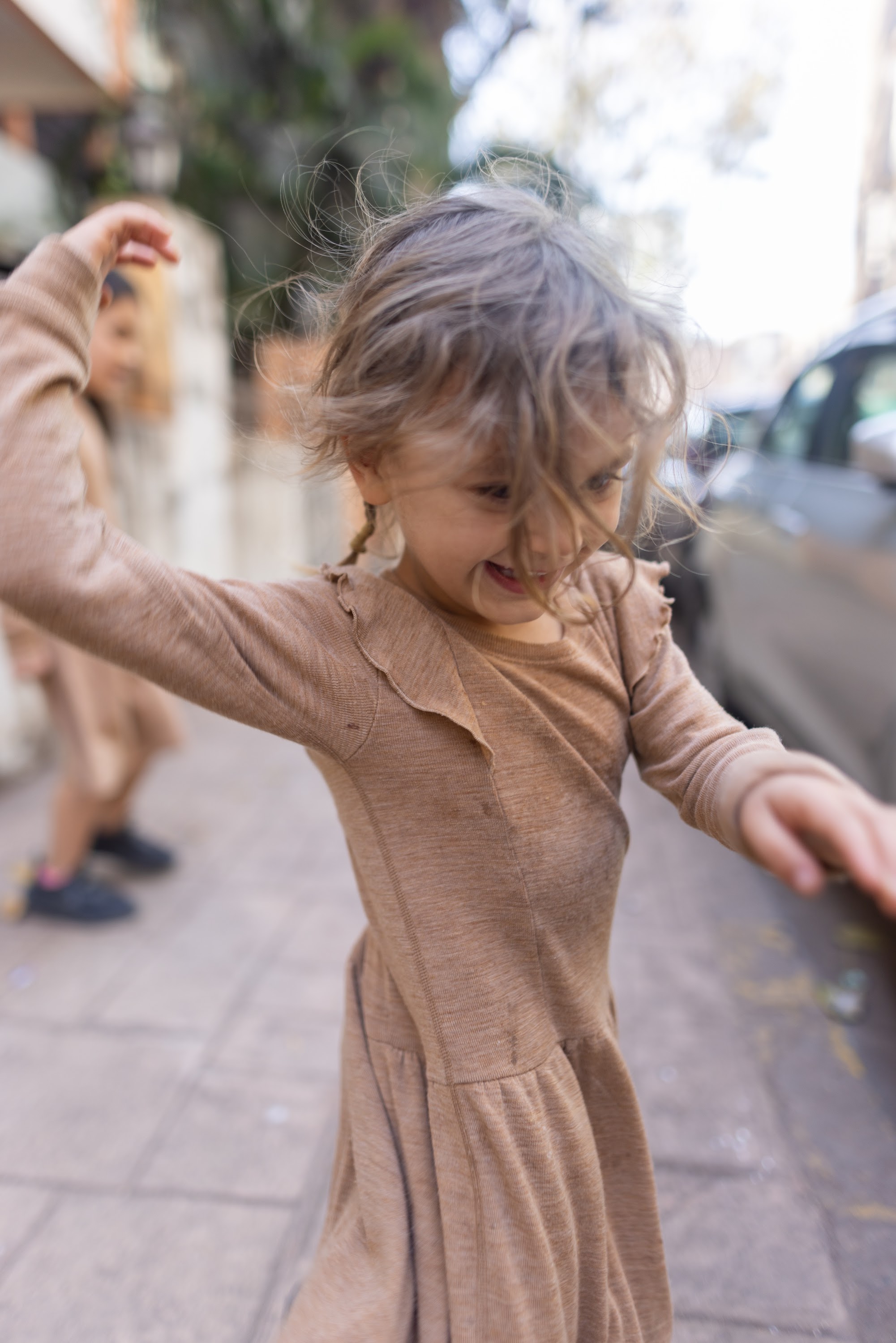 Joyful Girl Spinning on City Sidewalk