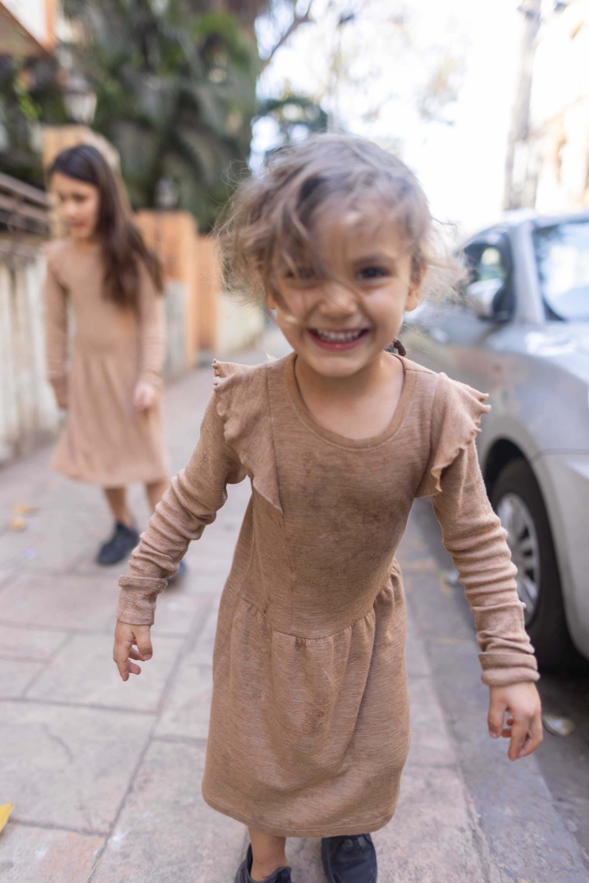 Smiling Girl in Tan Dress on Sidewalk