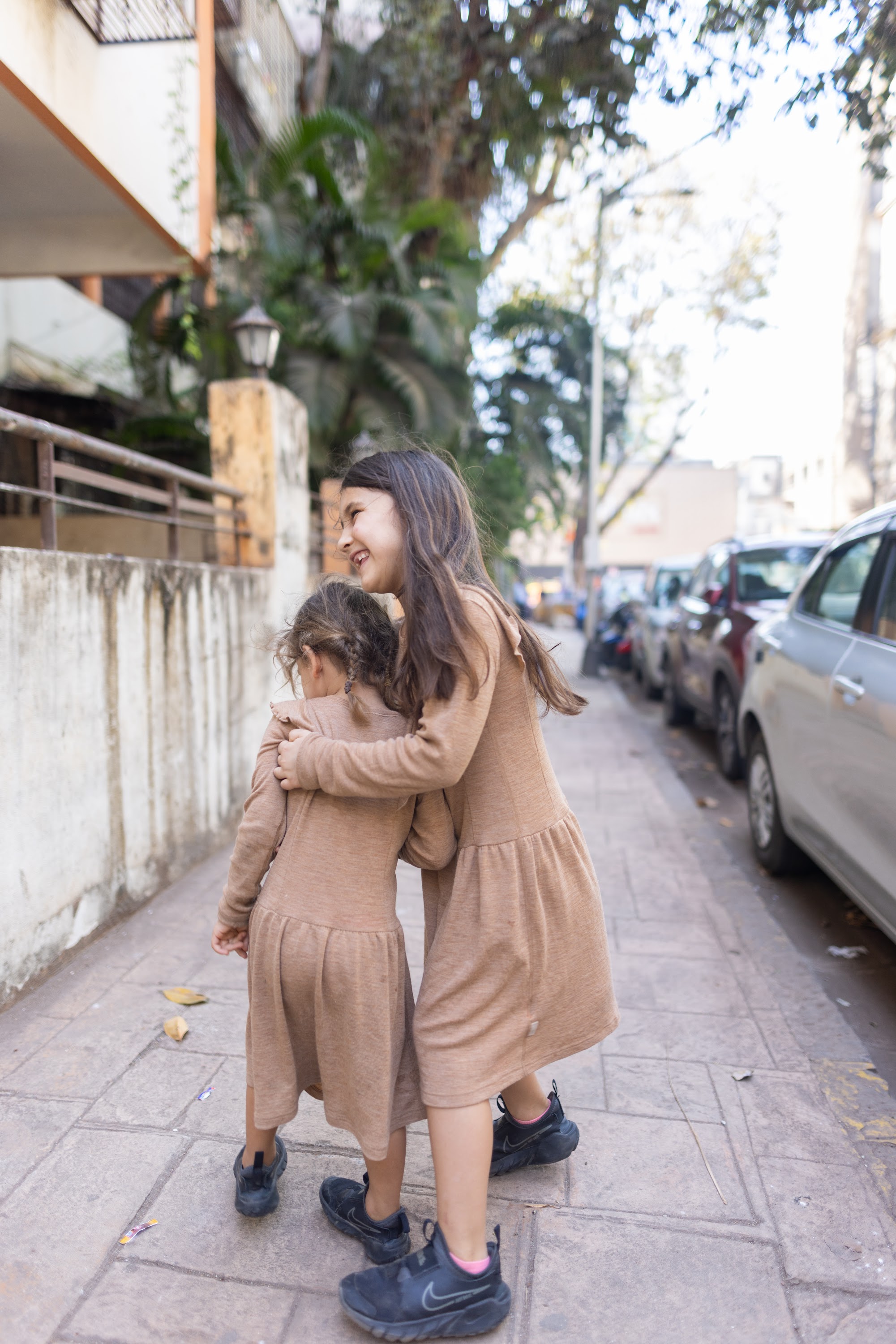 Two Girls Hugging on a City Sidewalk