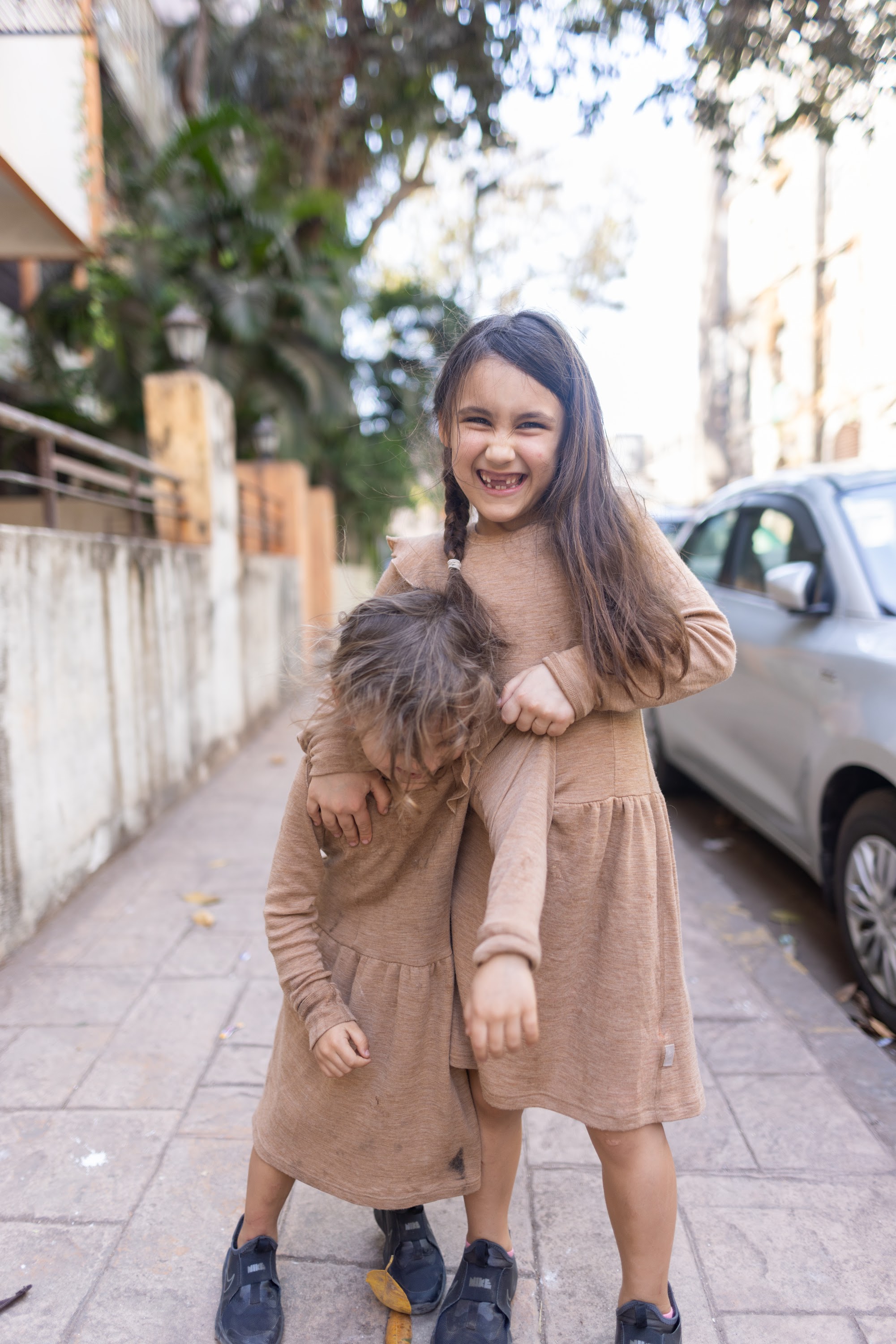 Two Girls Hugging on a Sidewalk