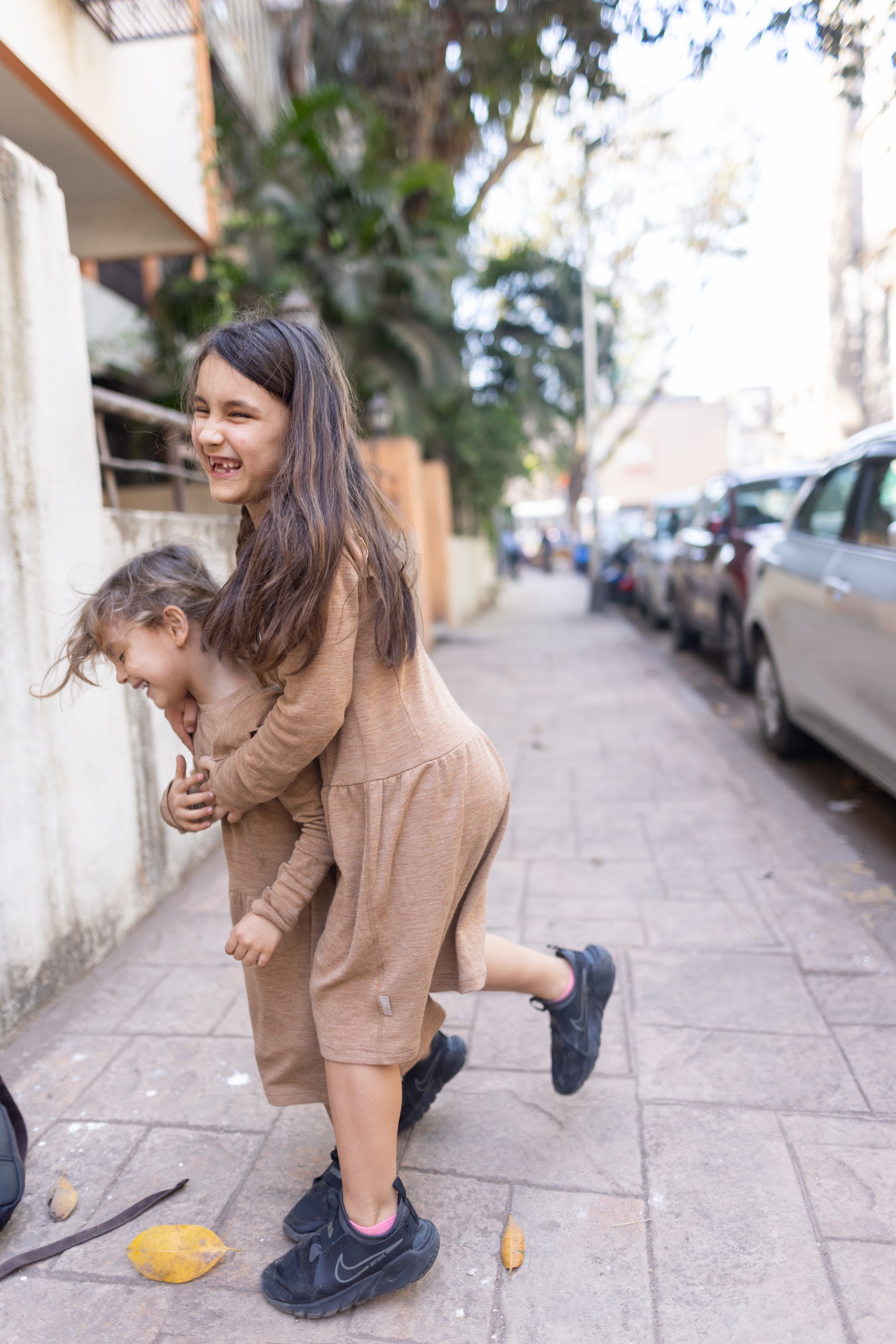 Playful Sisters on a City Sidewalk