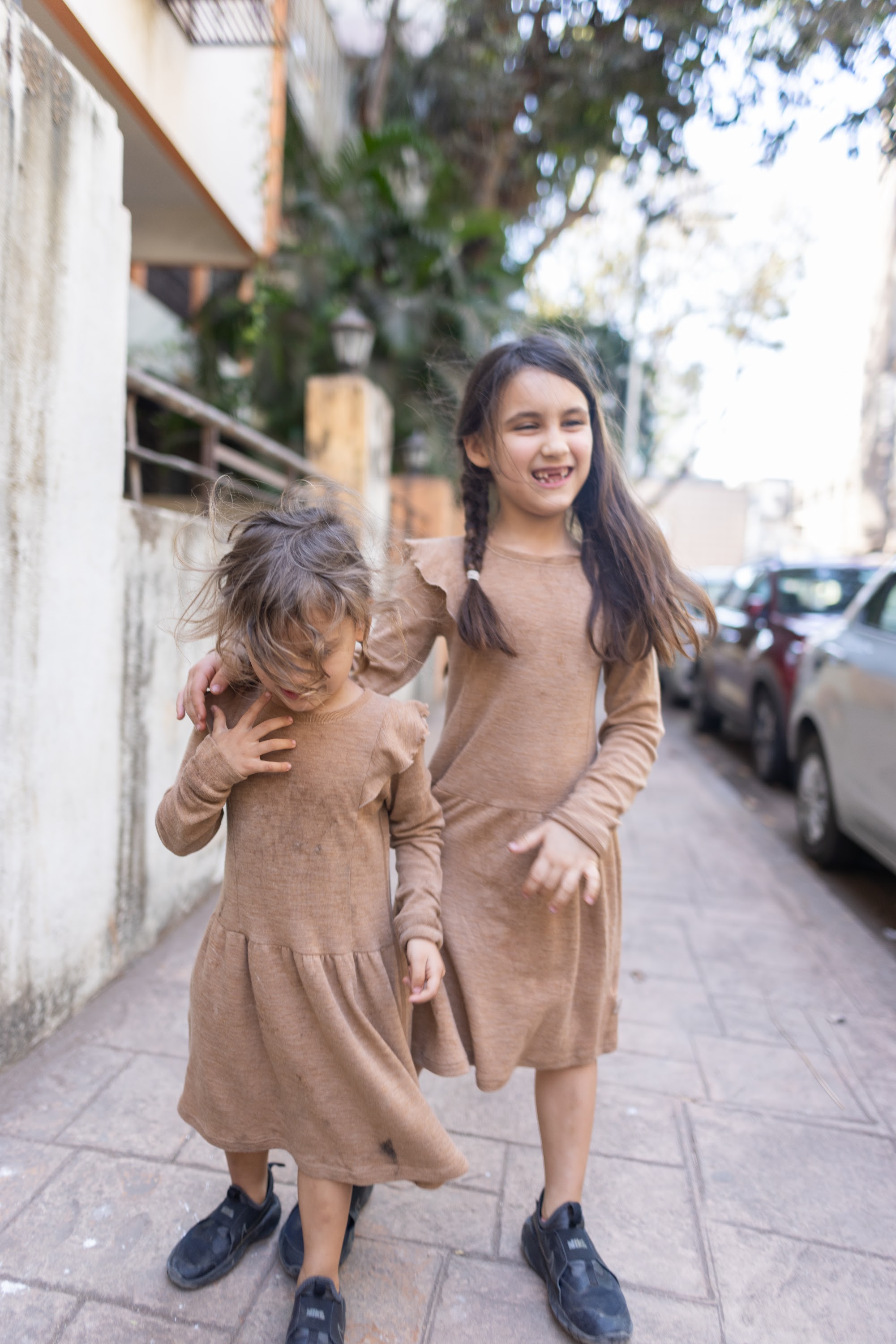 Two Girls in Matching Dresses Walking on a Sidewalk
