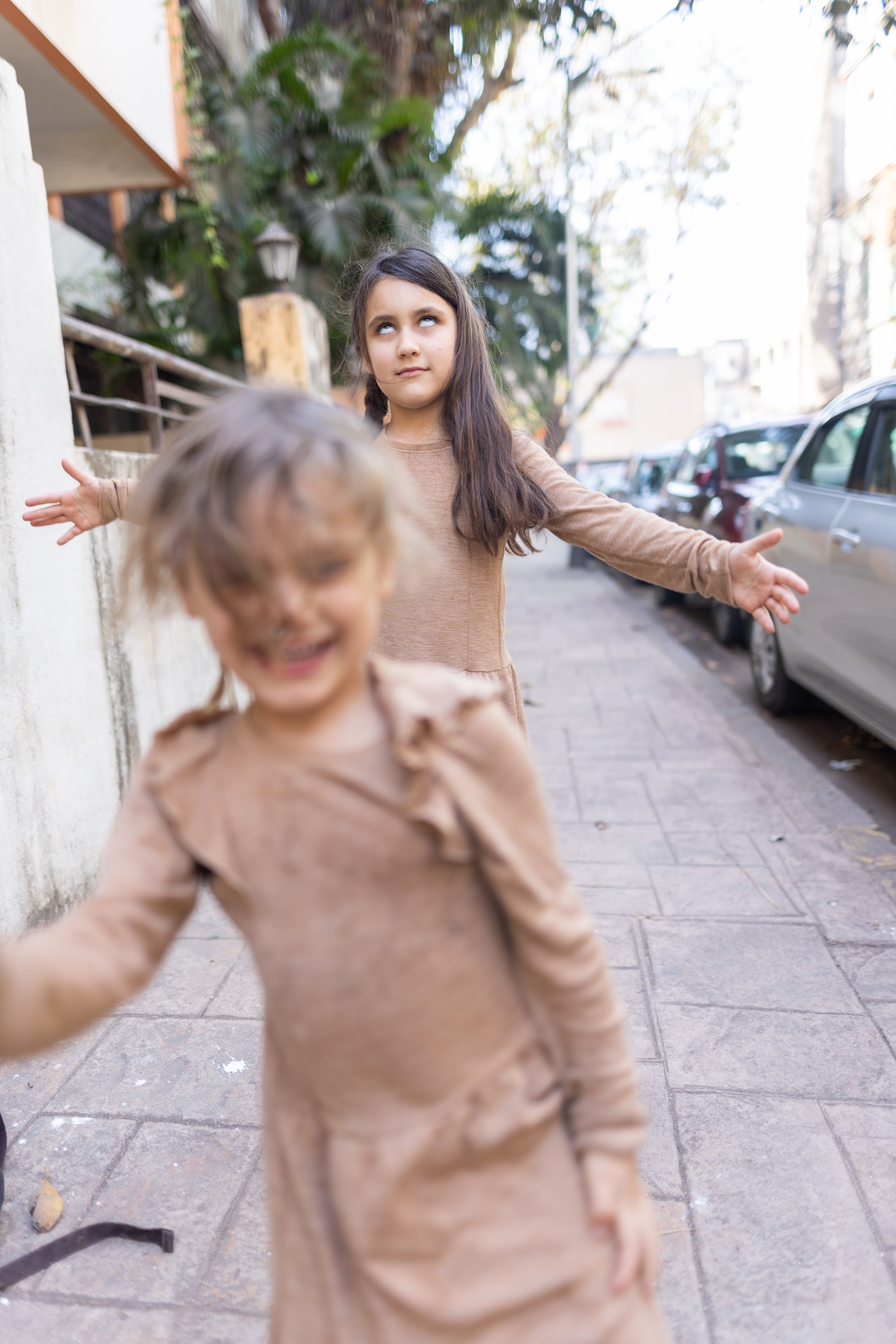 Two Girls Playing on a City Sidewalk
