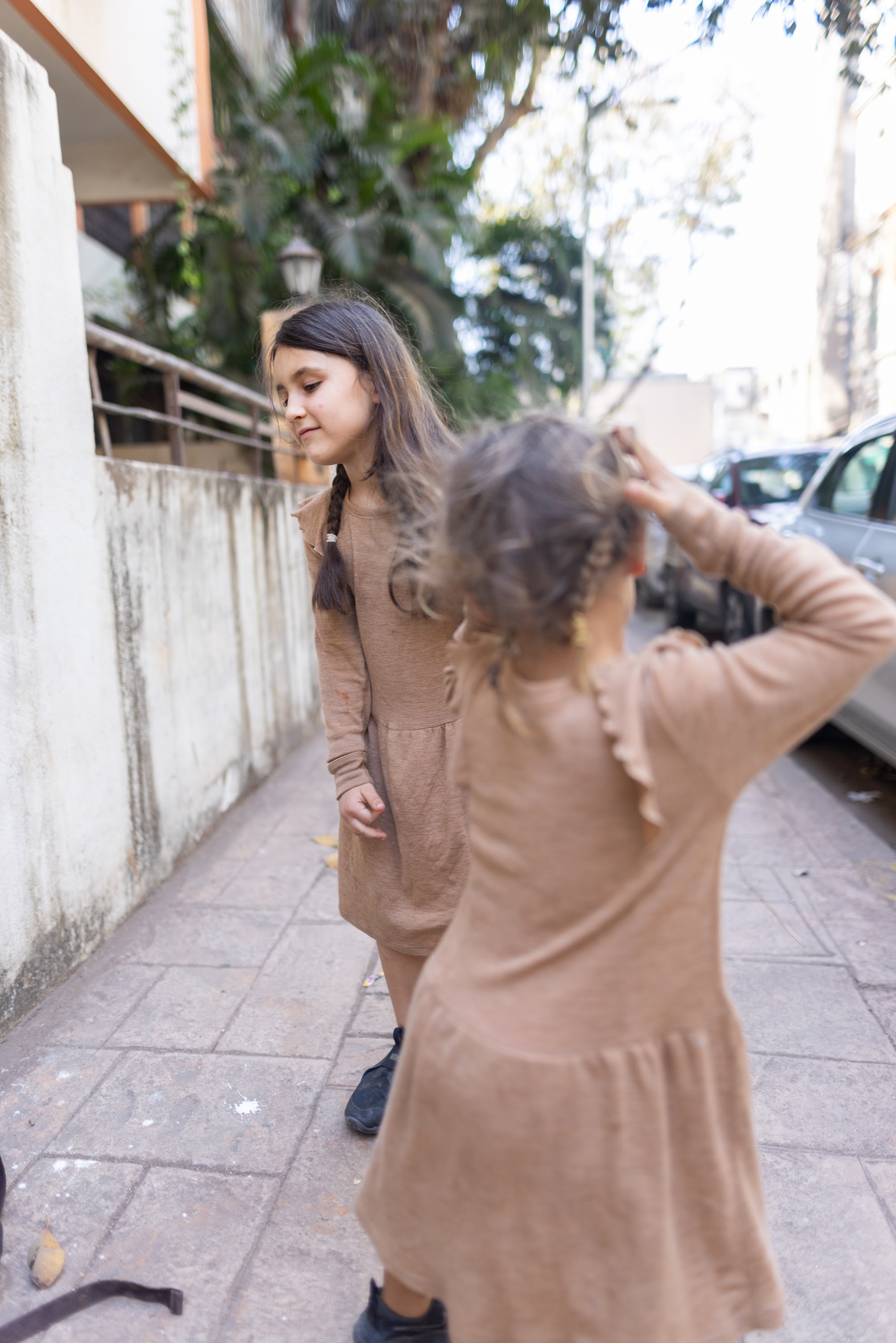 Two Girls in Matching Dresses on a City Sidewalk