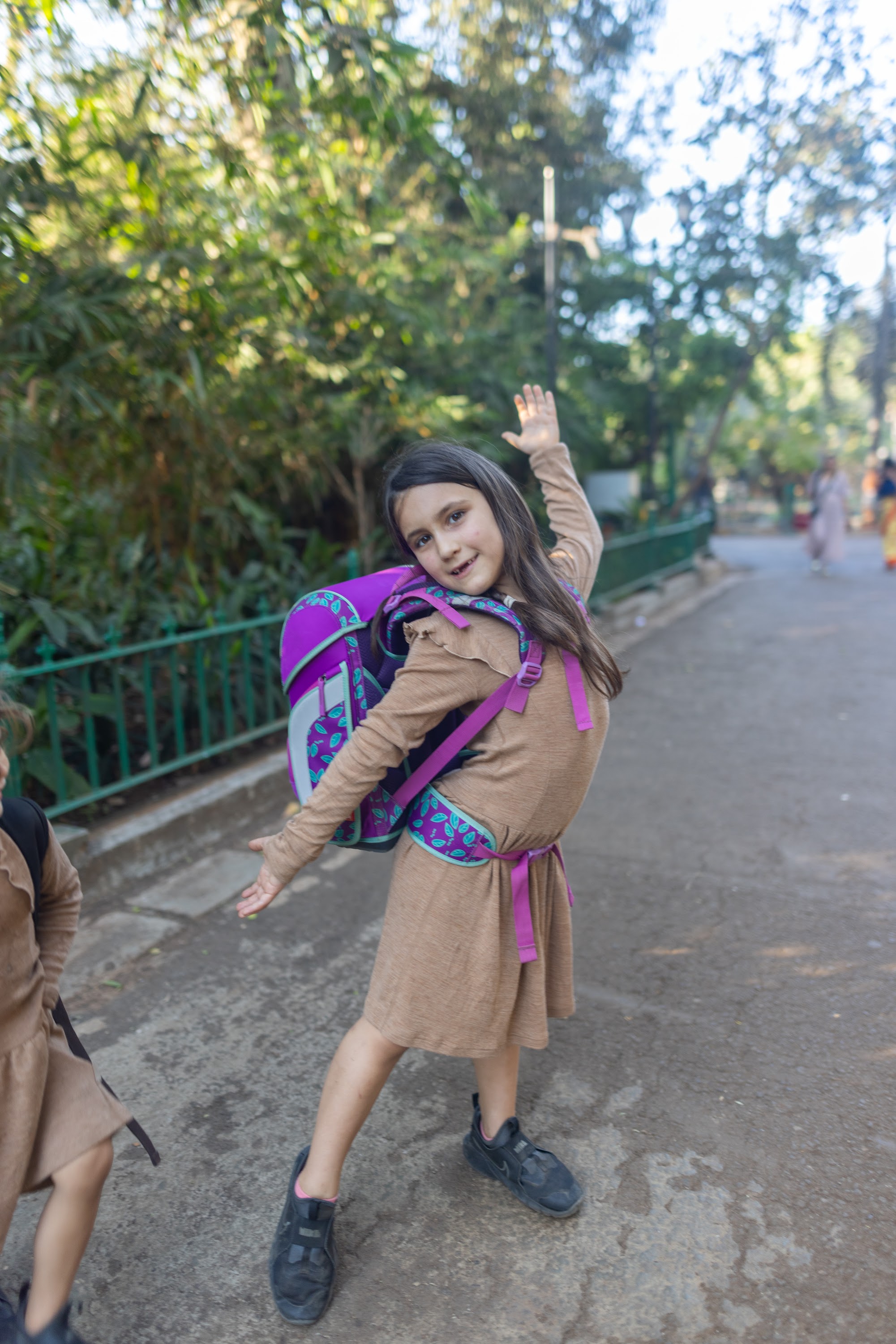 Girl Waving with Backpack on Path