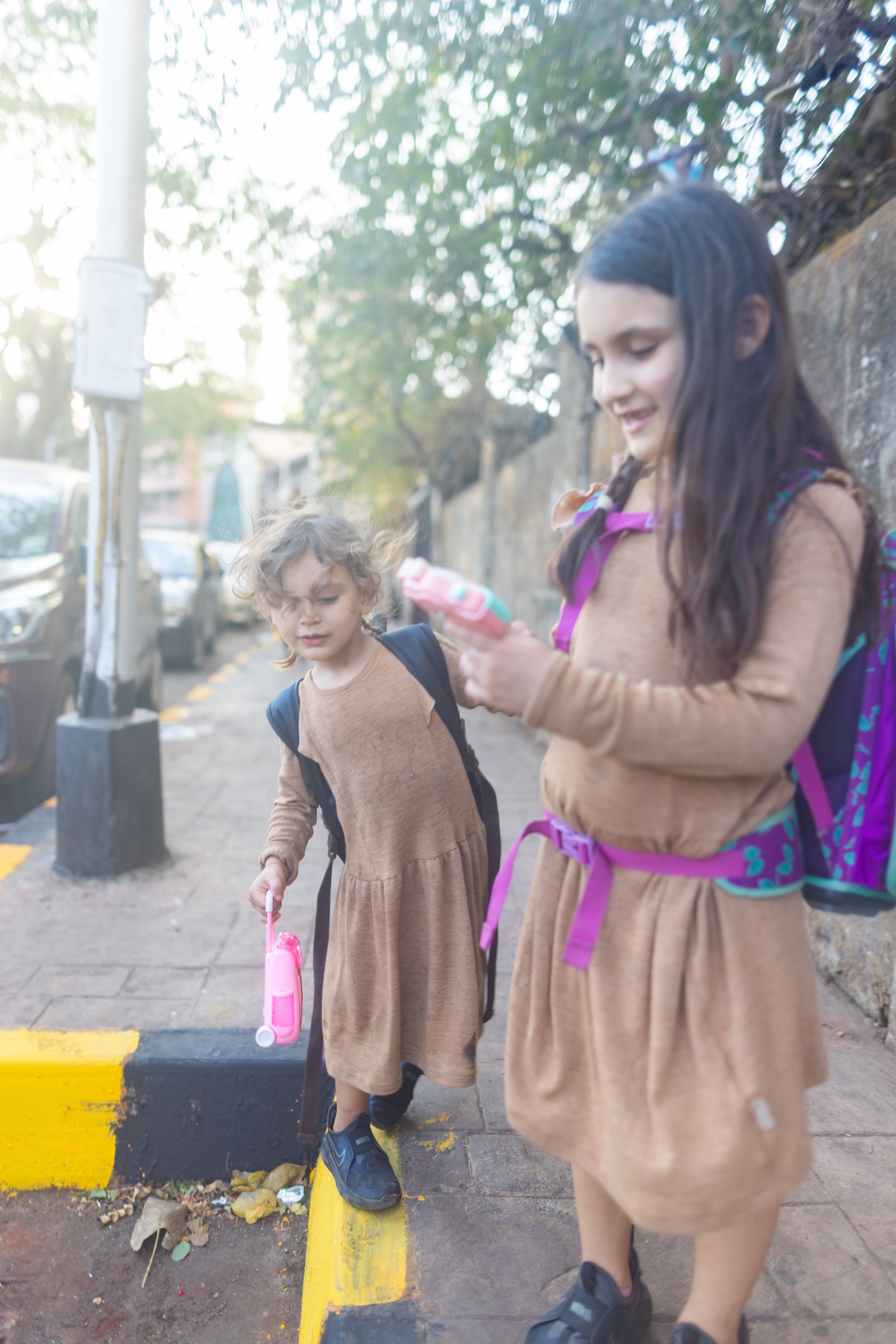 Two Girls in Matching Dresses Walking on a Sidewalk