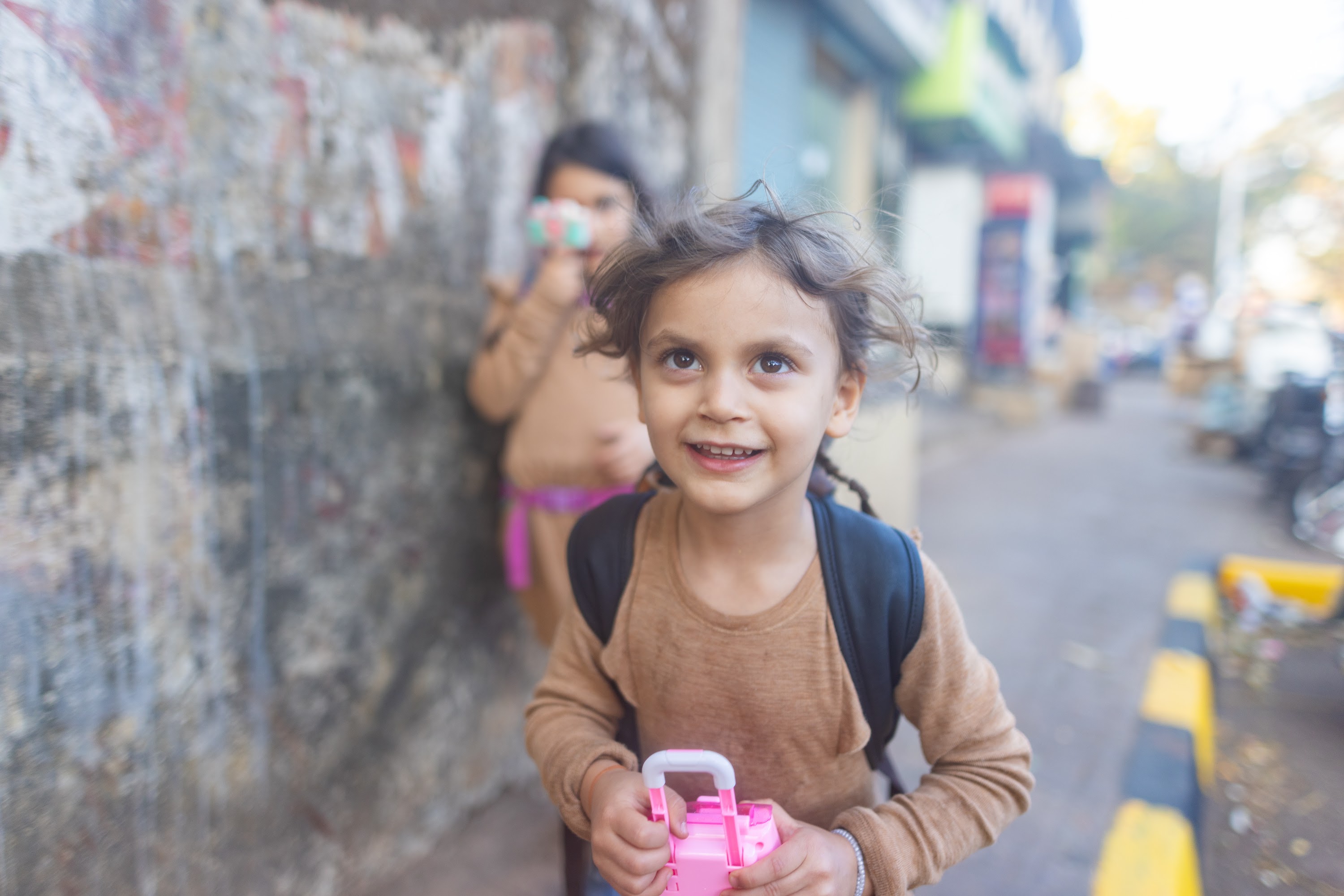 Smiling Girl Holding Pink Toy on Street
