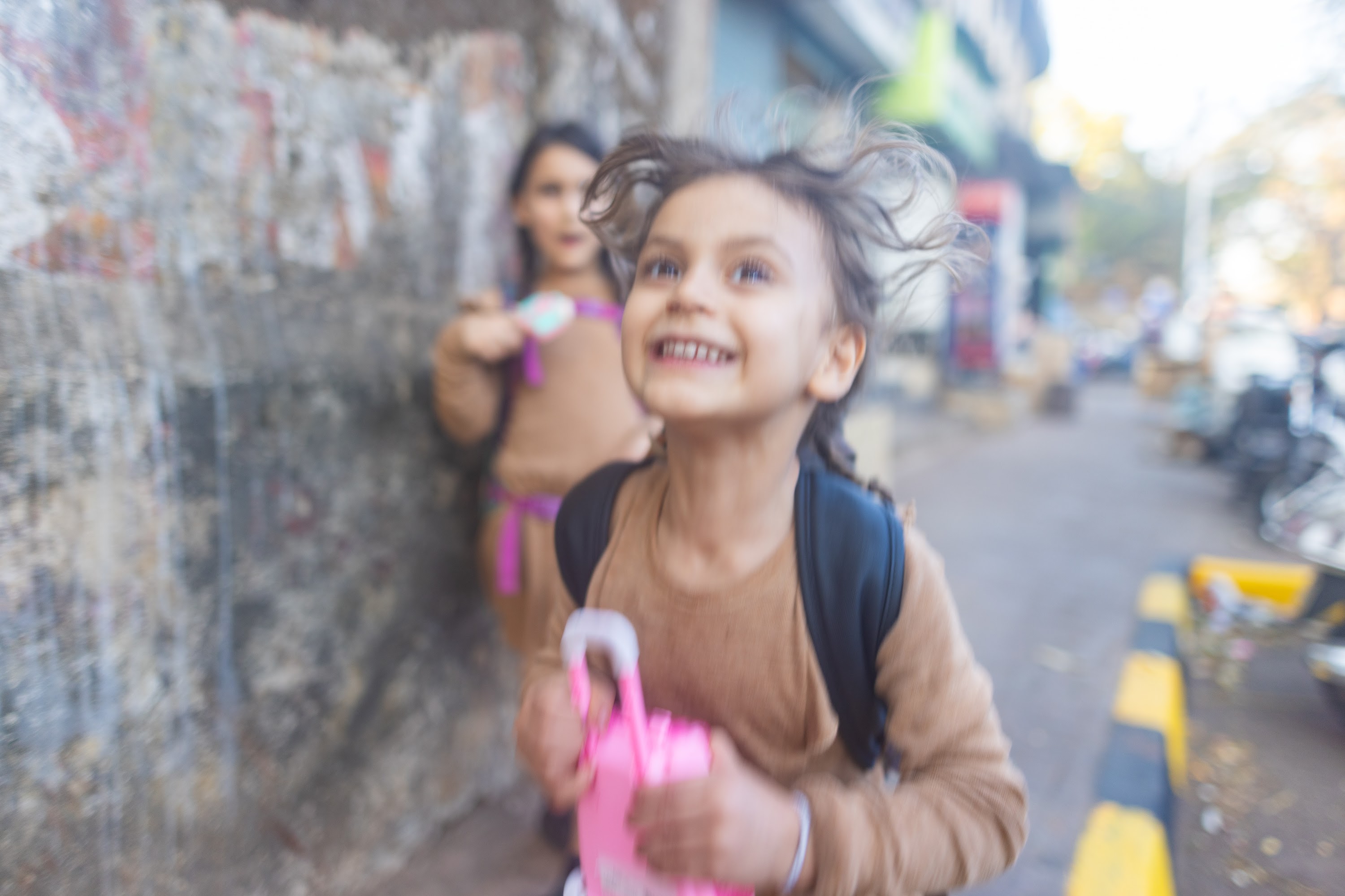 Smiling Girl Running on Street with Friend