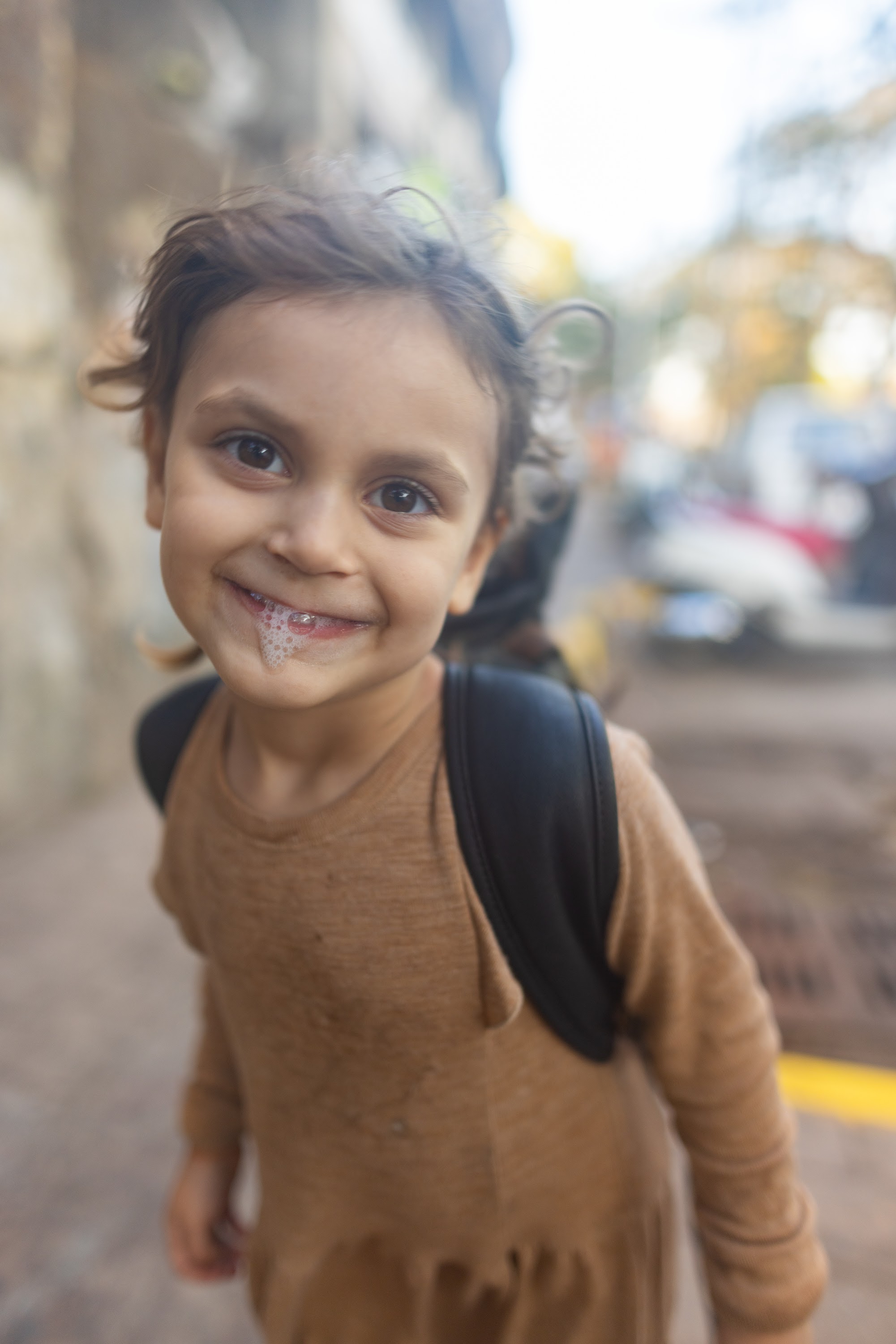 Smiling Child with Backpack on Street