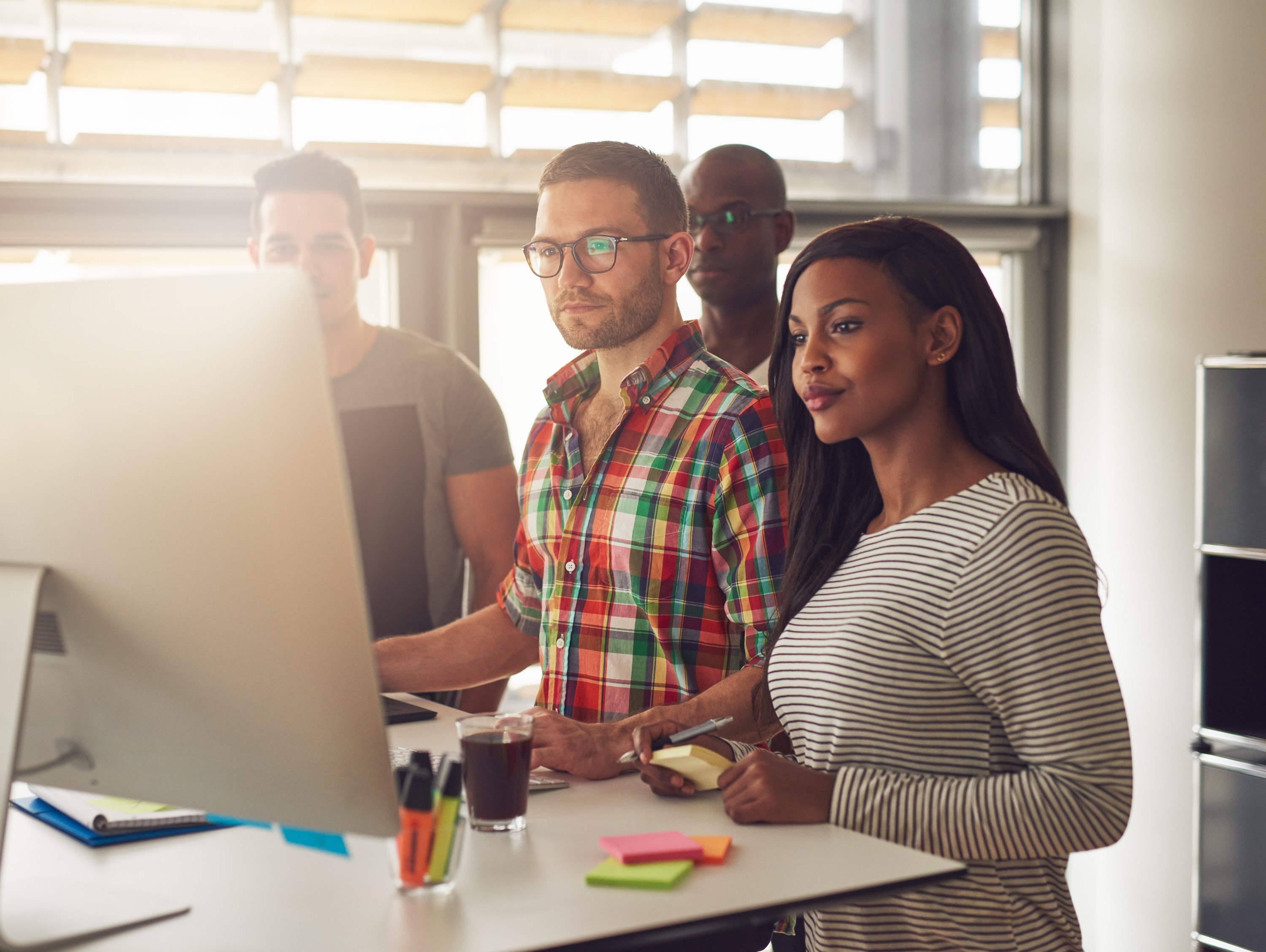 four-diverse-workers-standing-next-to-computer-2023-11-27-05-17-18-utc.jpg