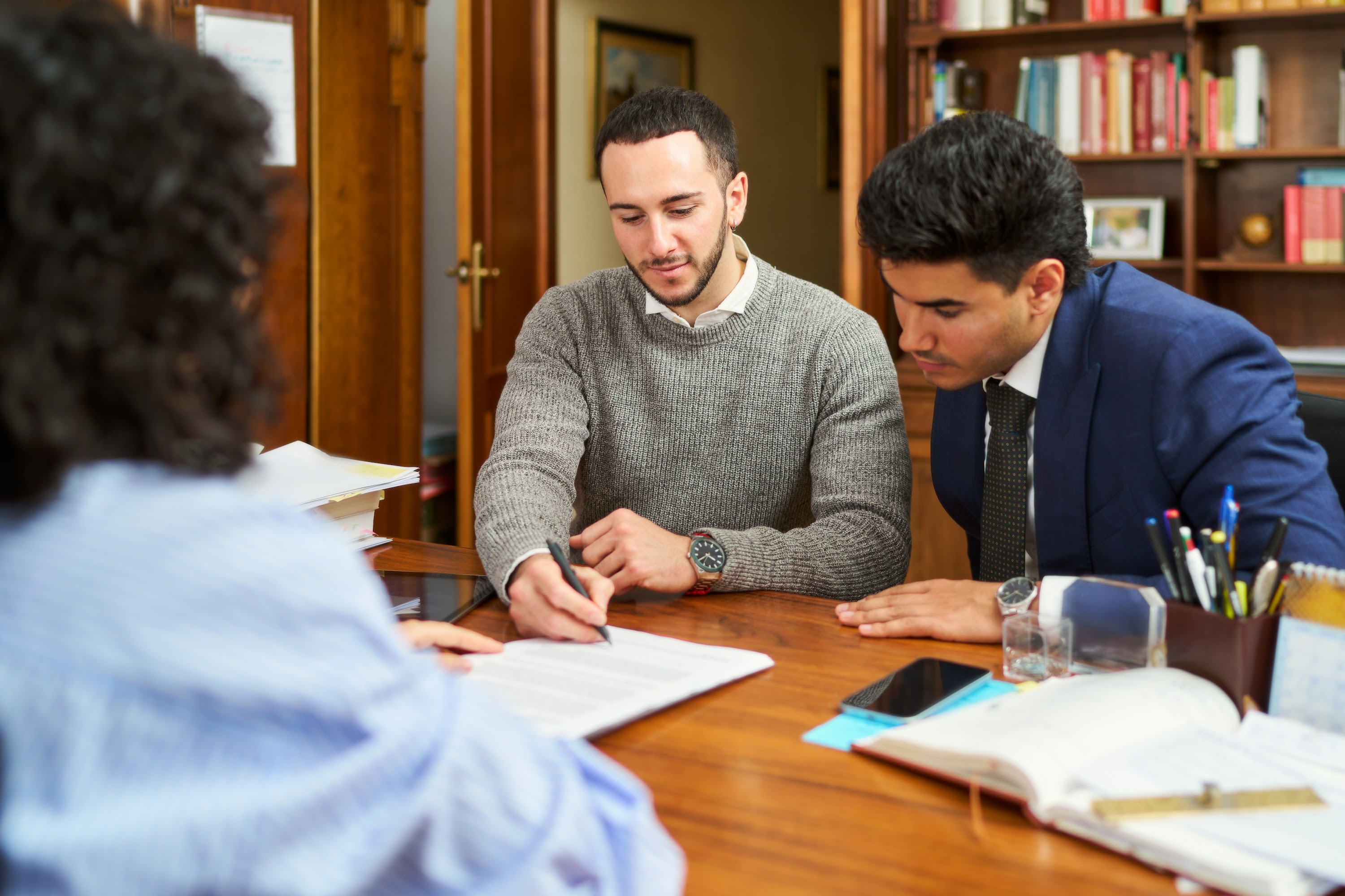 three-people-are-sitting-at-a-table-with-papers-an-2024-06-06-17-54-11-utc.jpg