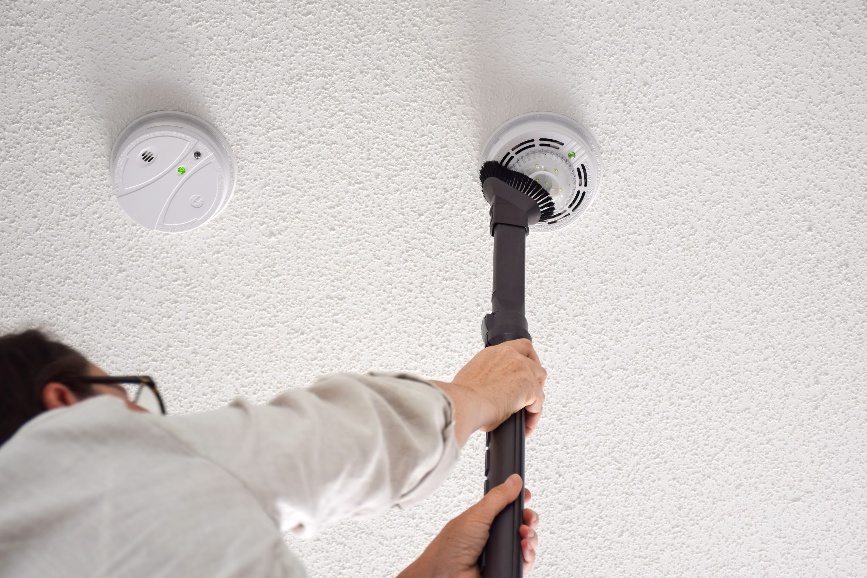 woman-vacuuming-smoke-and-carbon-monoxide-detector-2023-11-27-05-15-18-utc.jpg