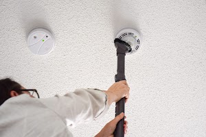woman-vacuuming-smoke-and-carbon-monoxide-detector-2023-11-27-05-15-18-utc.jpg