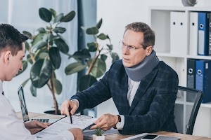 businessman-in-neck-brace-sitting-at-table-and-poi-2023-11-27-05-01-36-utc (1).jpg