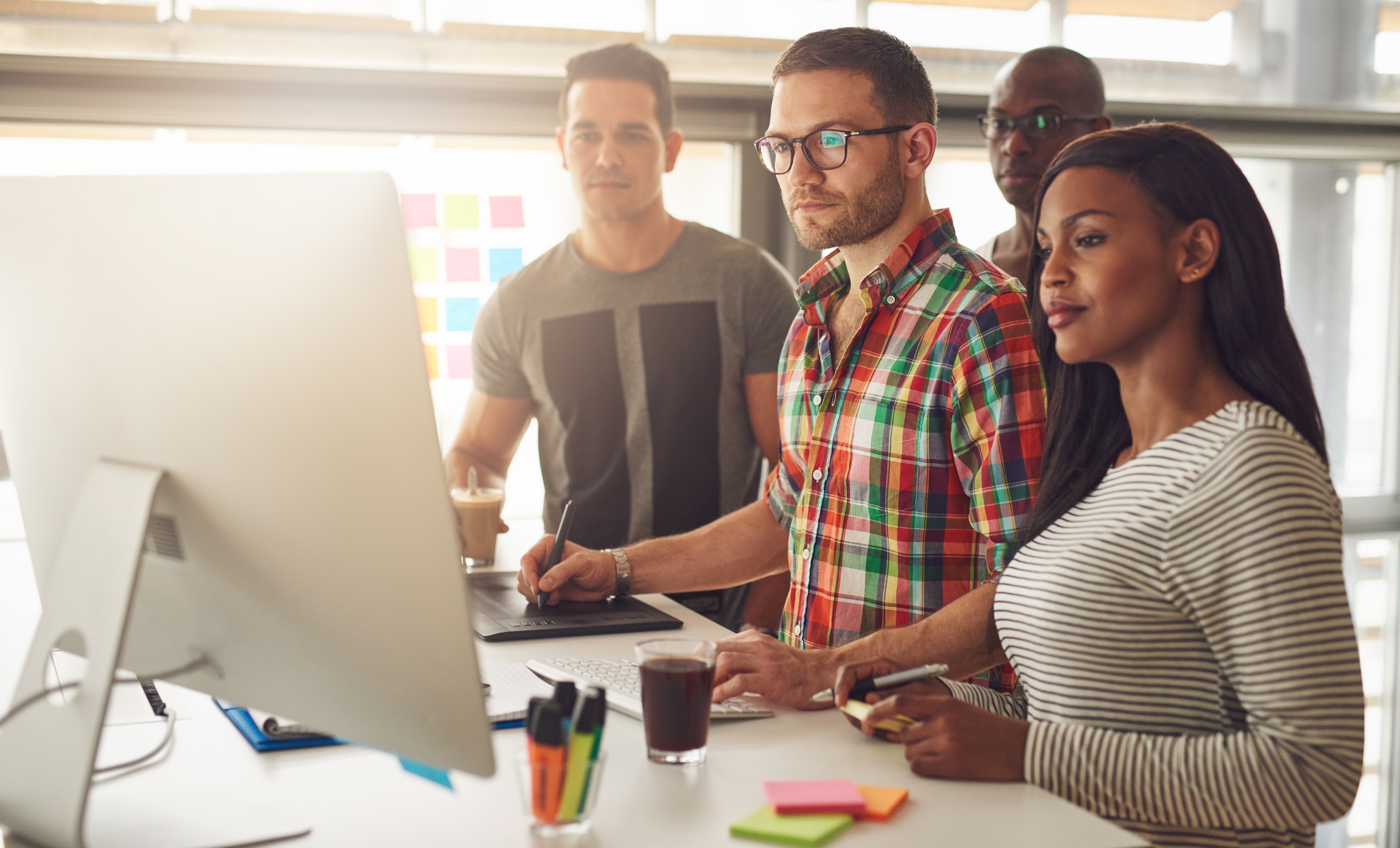 four-young-workers-standing-around-computer-2024-09-13-23-21-13-utc.jpg