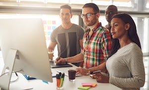 four-young-workers-standing-around-computer-2024-09-13-23-21-13-utc.jpg